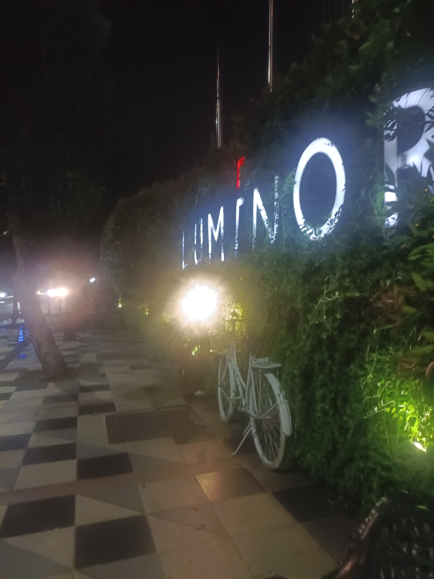 Nighttime street scene captured with illuminated LUMINO sign, bicycle