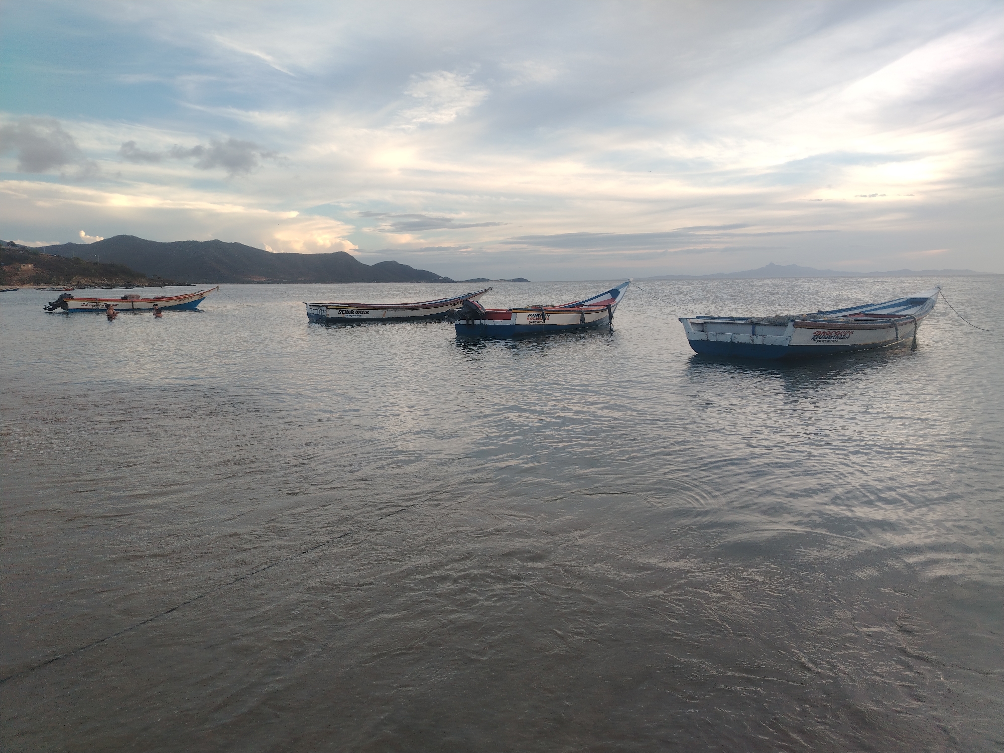 Fishing boats anchored at sunset off a calm coastal bay