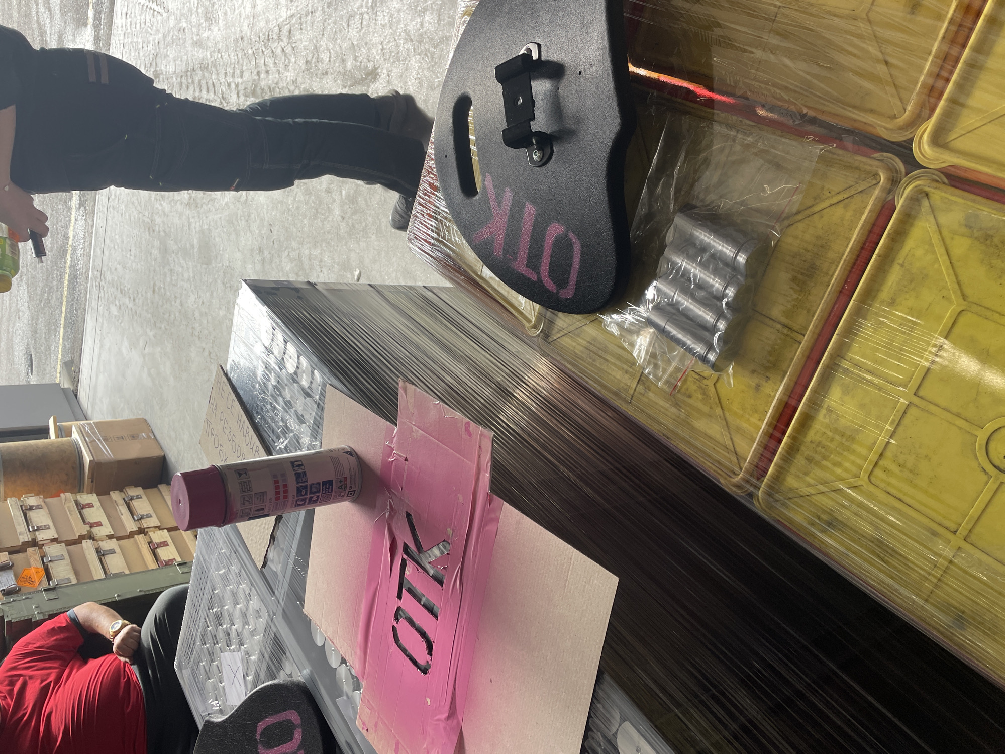 Workers spray paint pink markings on container in Bulgarian warehouse