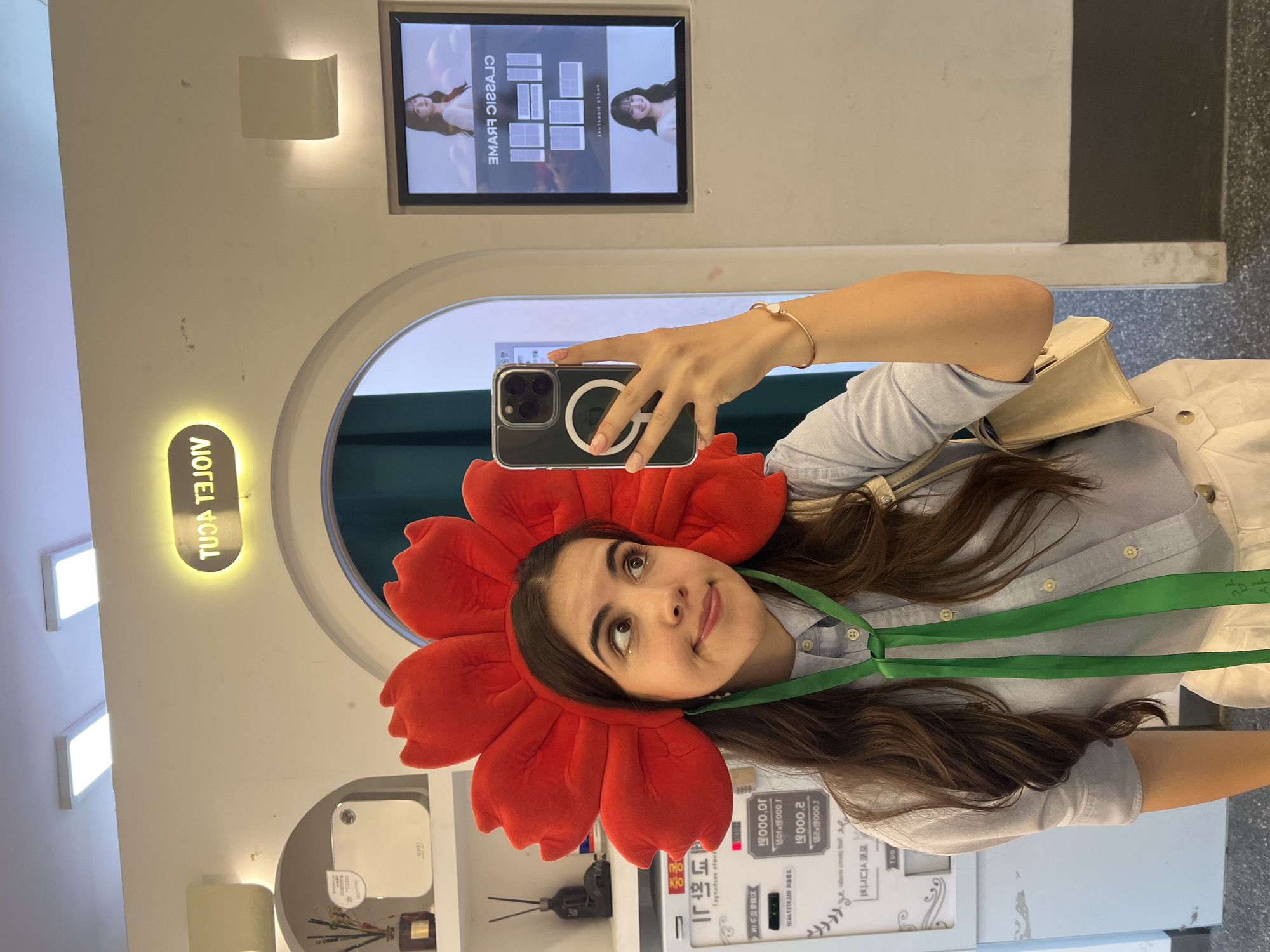 Woman takes selfie wearing red flower headpiece in Seoul photo booth