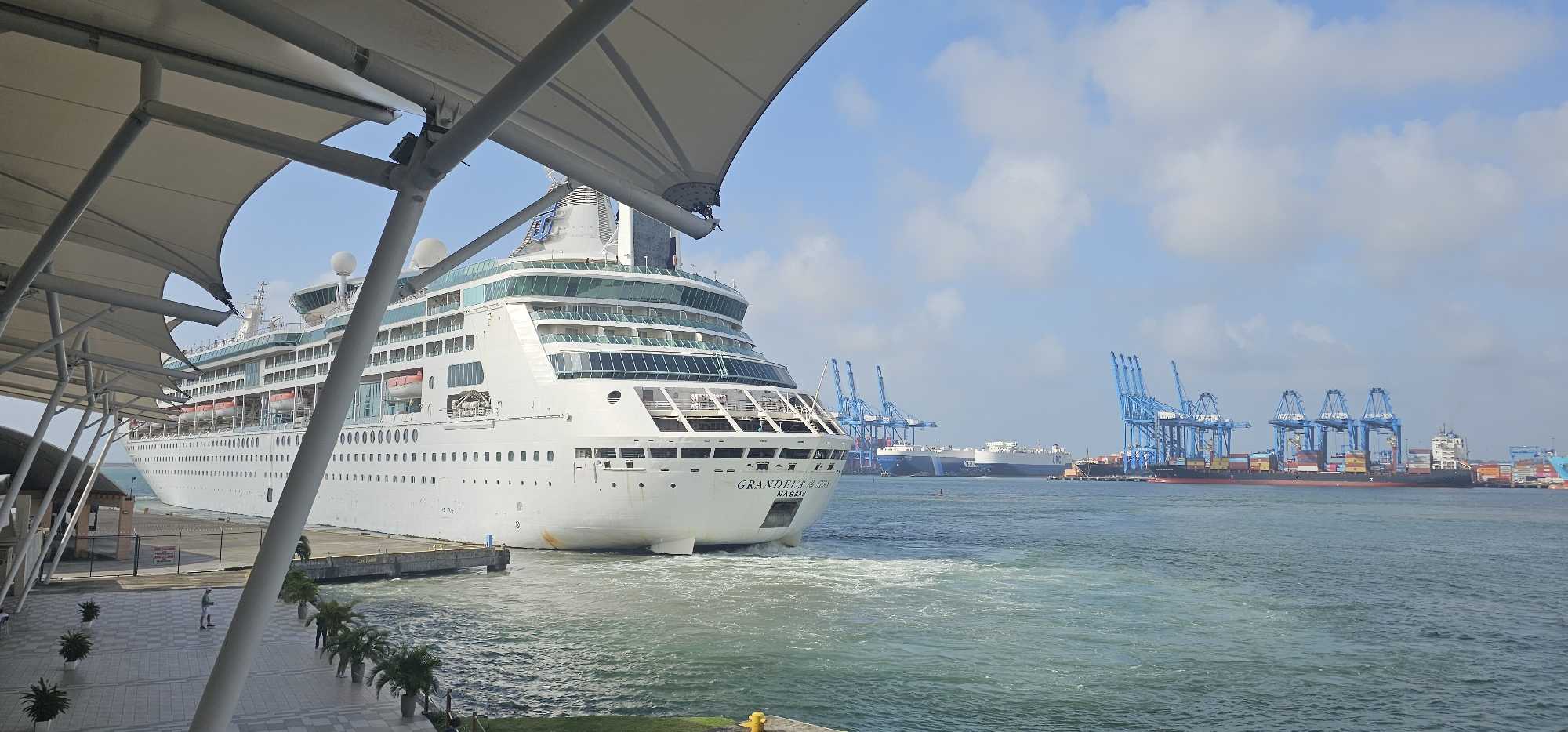 Cruise ship docked at port, framed by waterfront dining canopy
