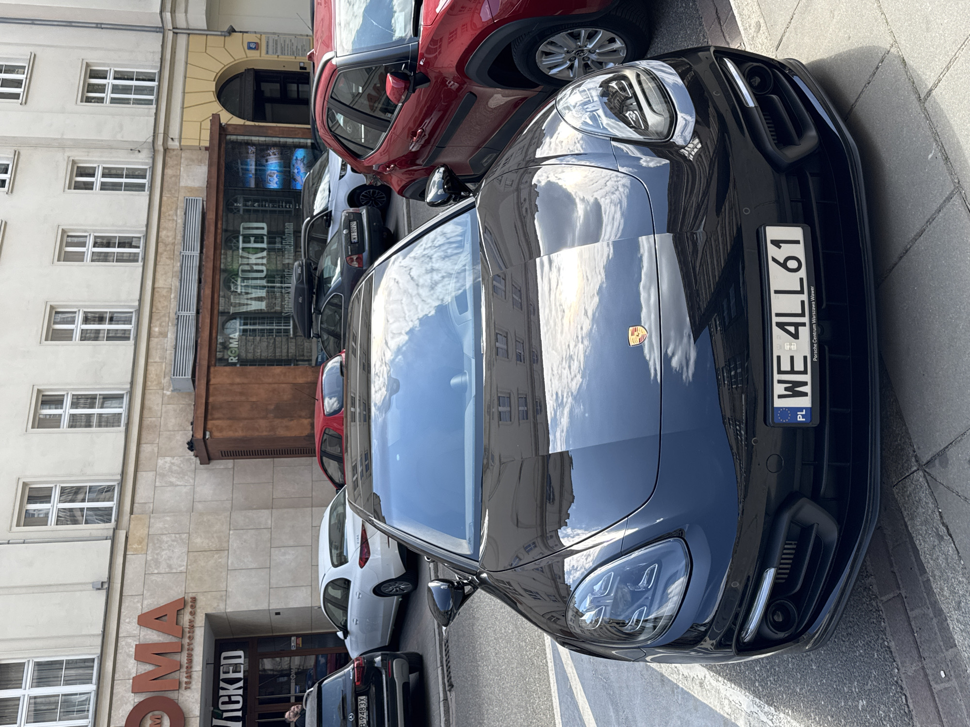 Black Porsche parked outside ROMA theater showing Wicked in Warsaw