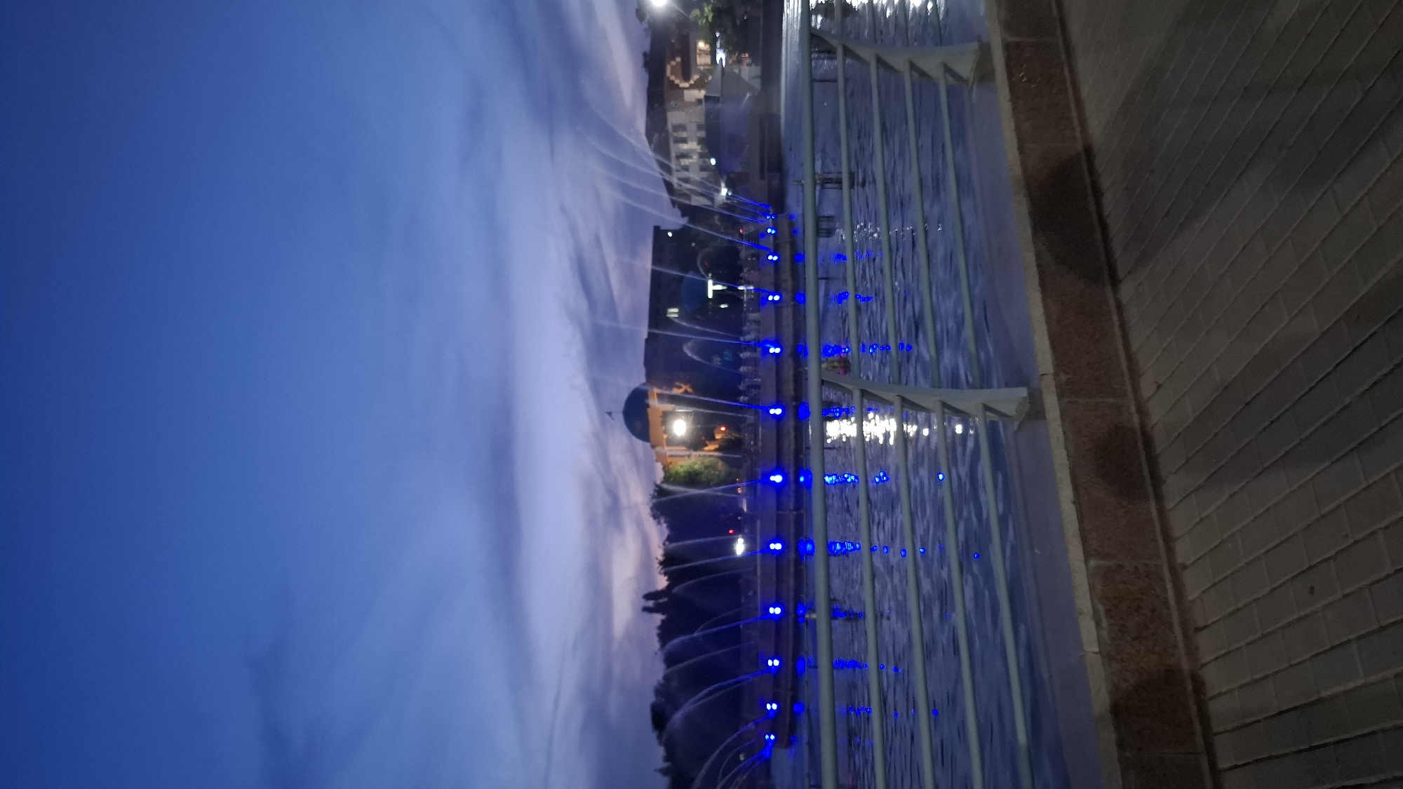 Shymkent park at dusk, fountains lit and evening setting in