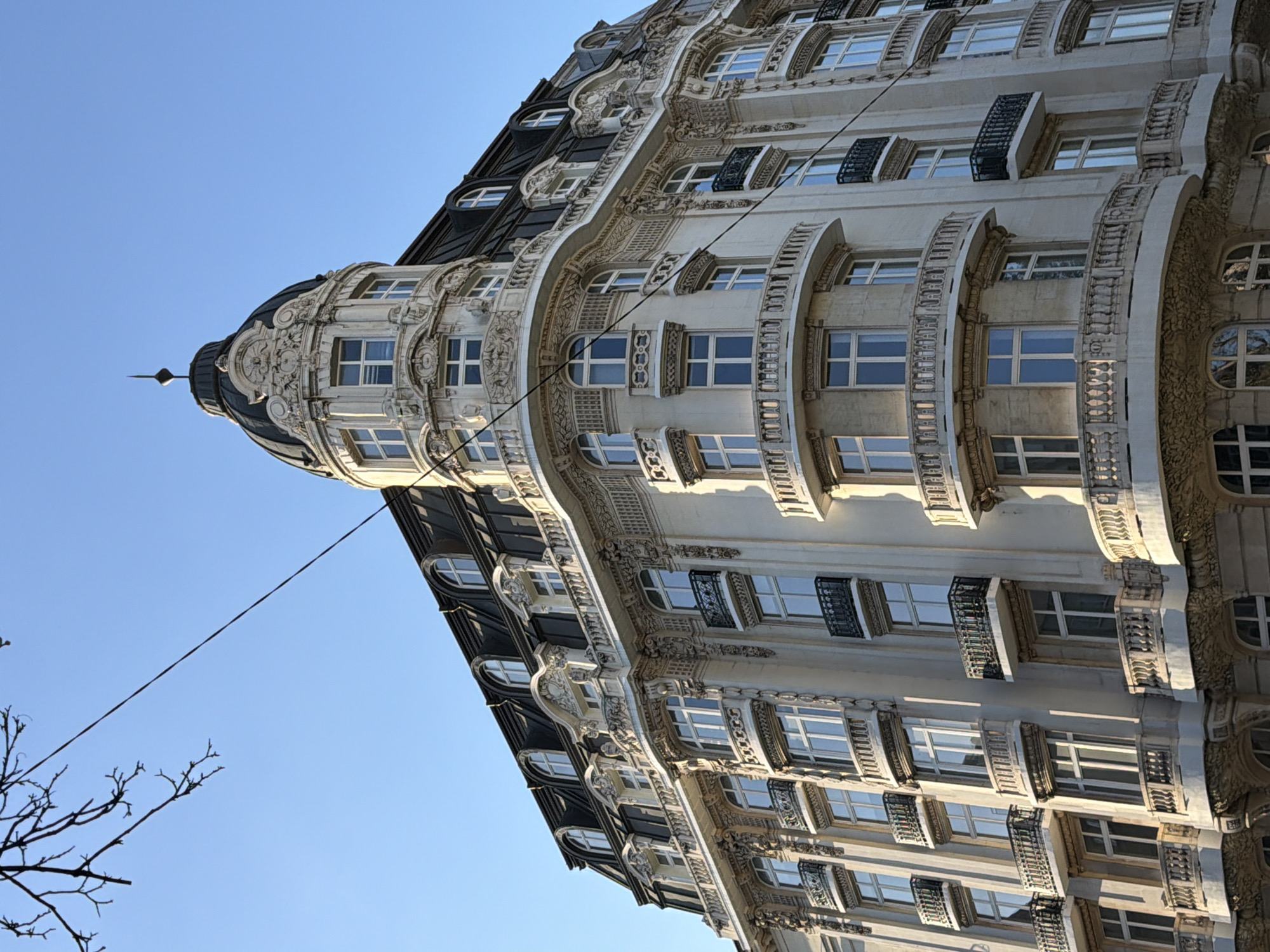 Ornate building and pink SUV documented in street scene