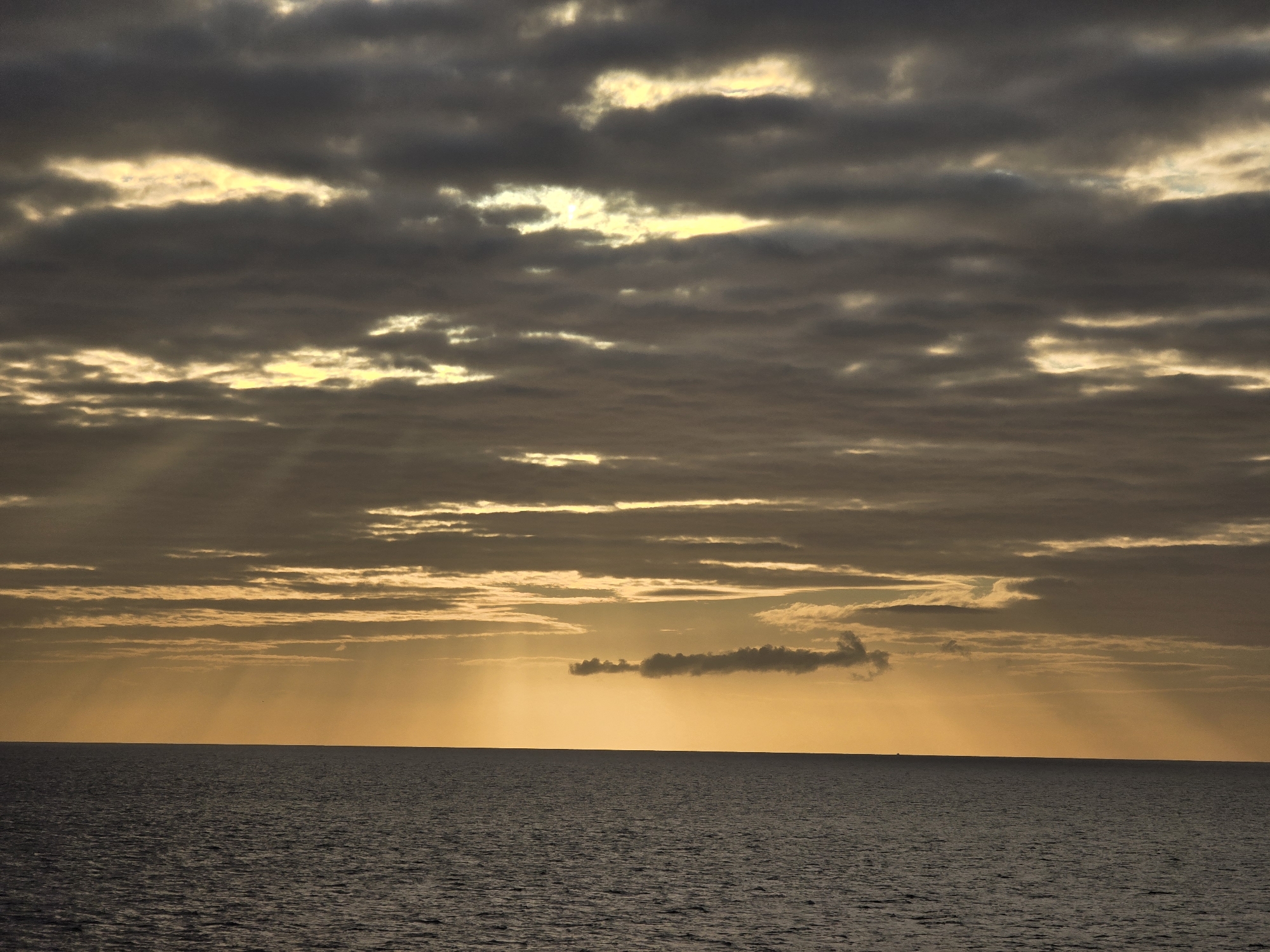 Sun breaking through clouds over the North Sea at dawn