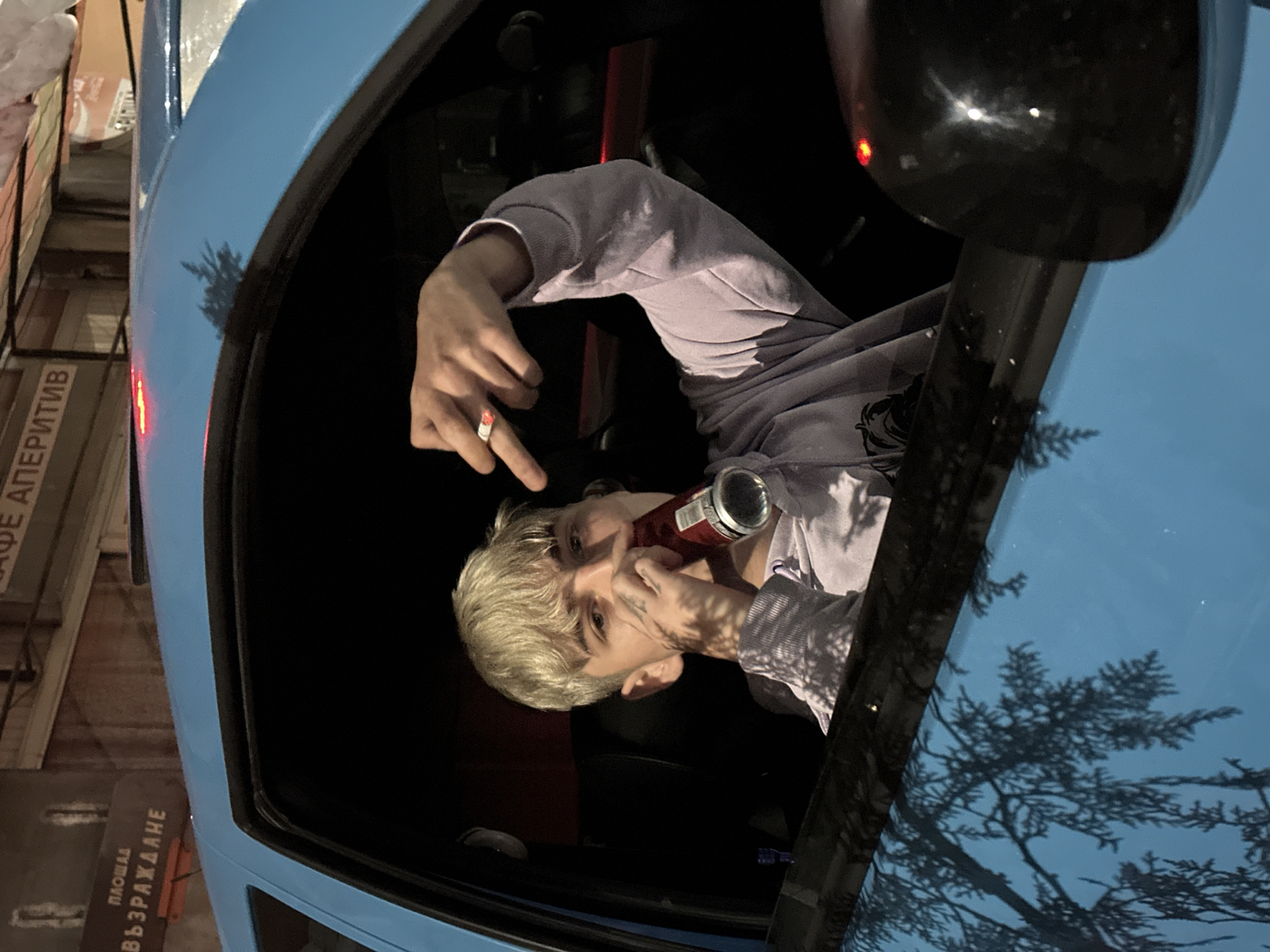 Person smoking, drinking in parked blue car in Velingrad