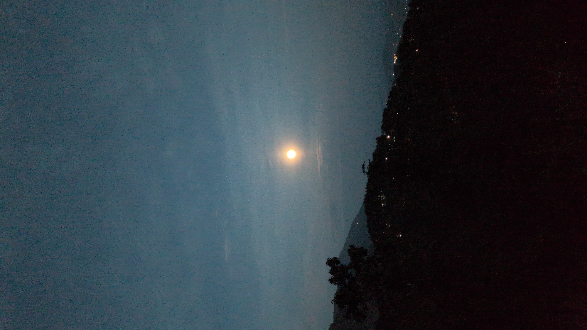Bright moon observed over Dharamkot mountains during daylight hours