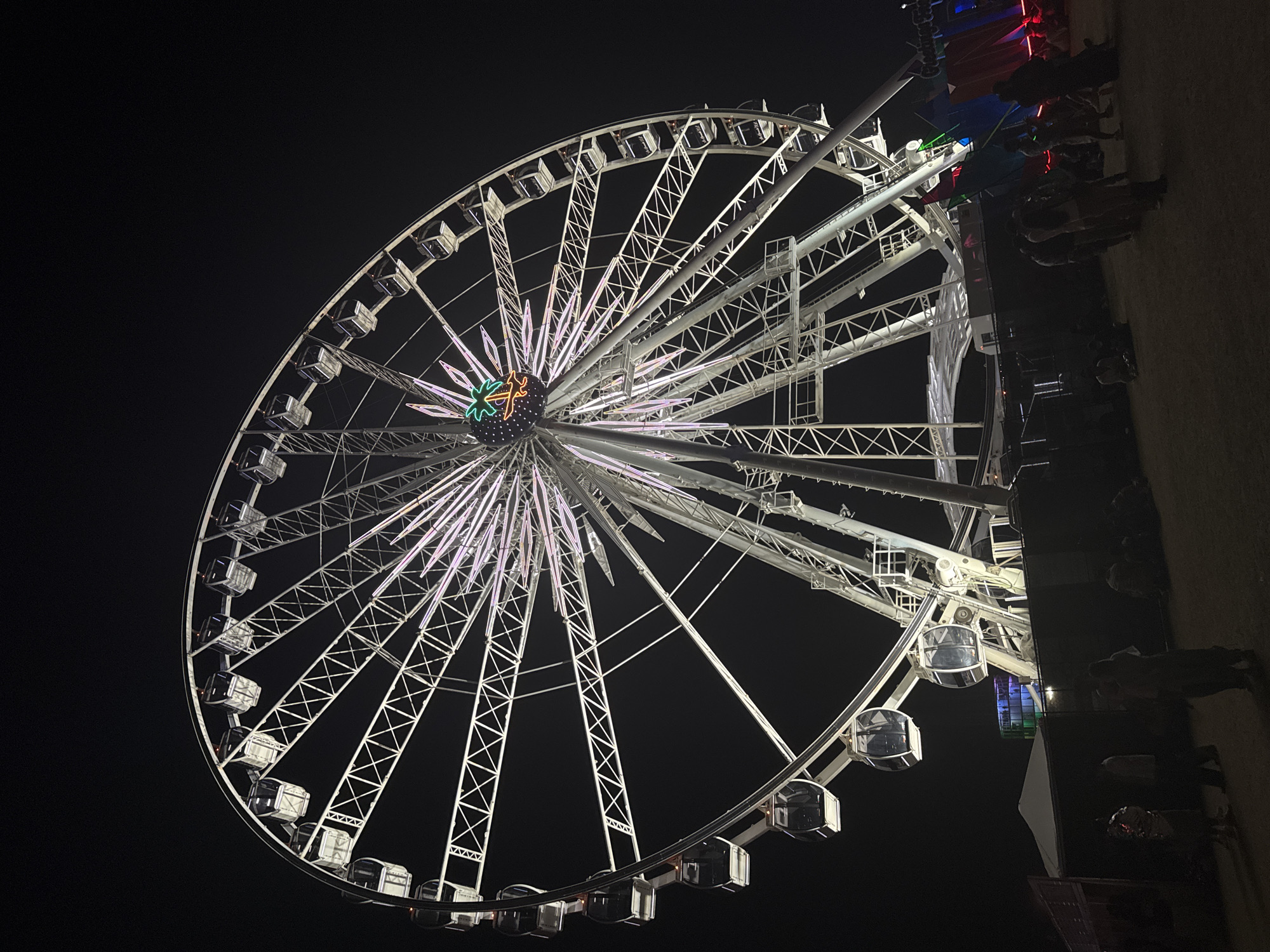 Illuminated Ferris wheel operates at night in Indio