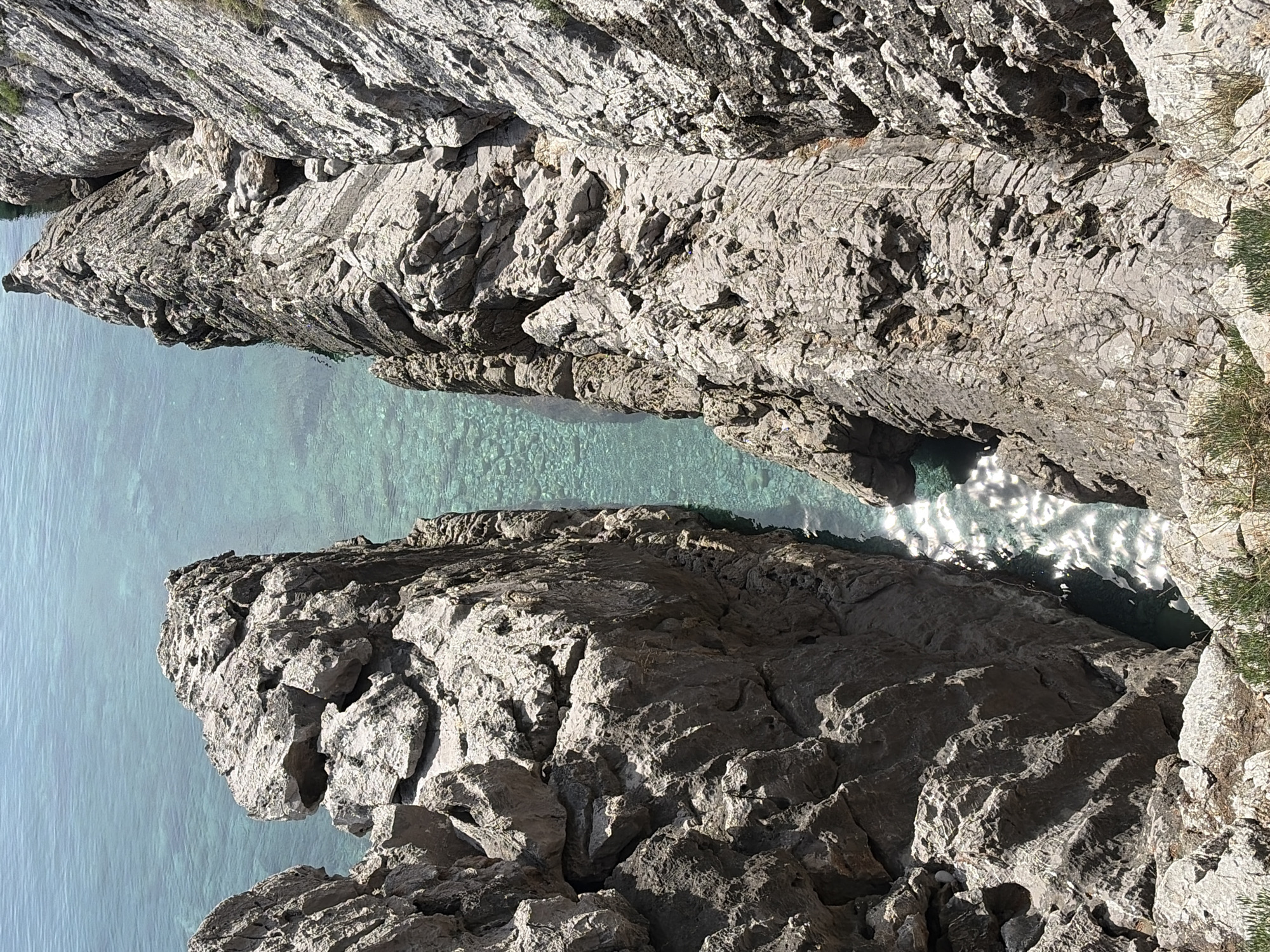 Person kneels on ledge overlooking water in Budva