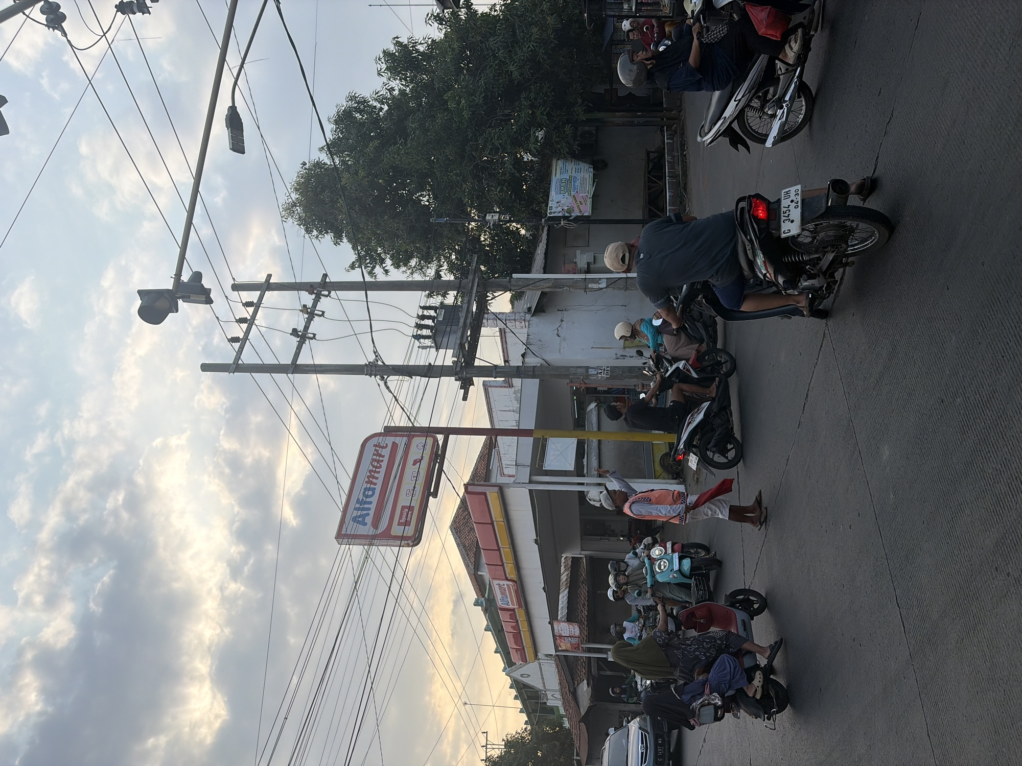 Street life at a Pekalongan junction — juice stalls, motorcycles, and big skies