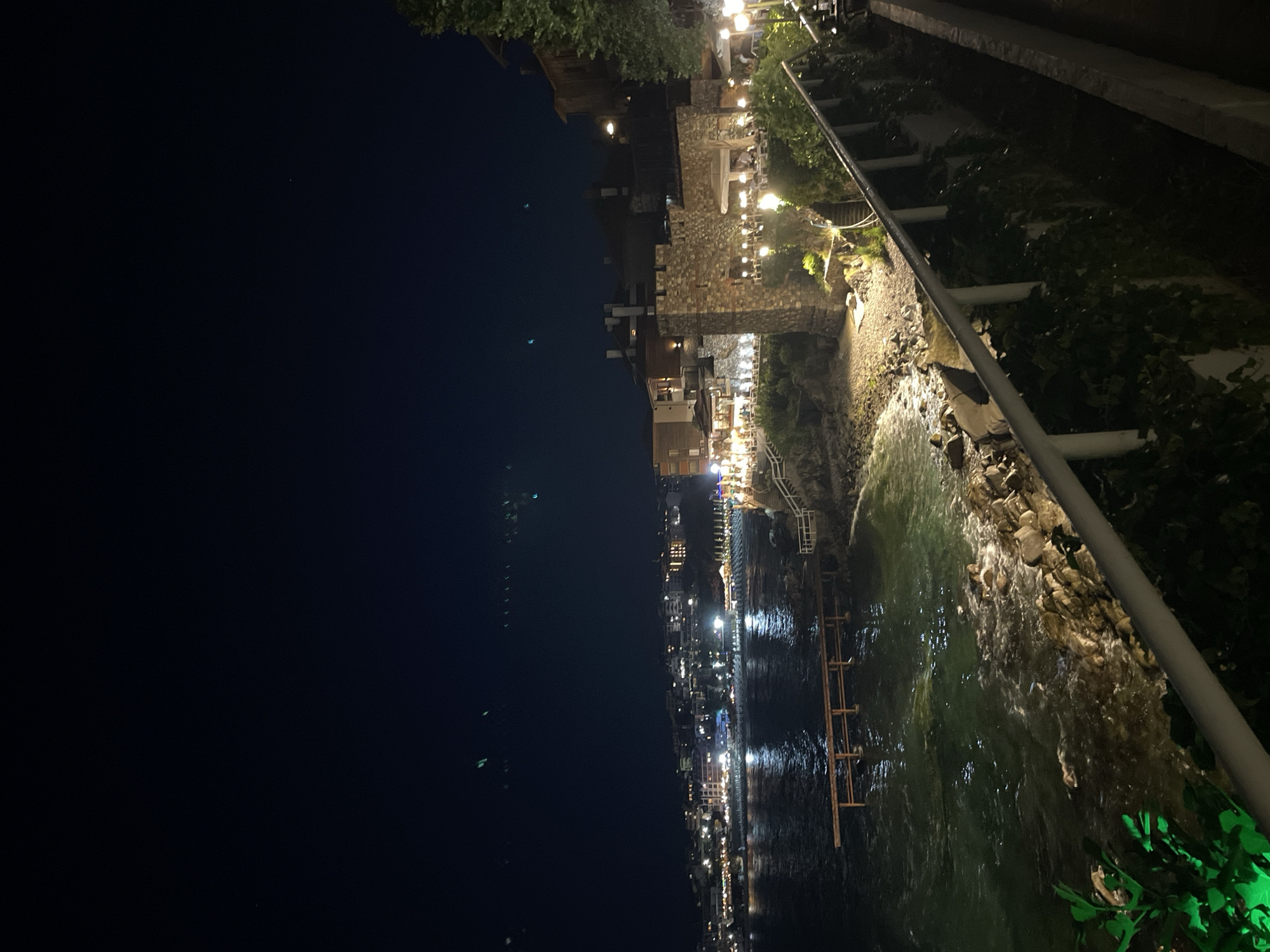 Nighttime coastal town lights reflect off calm water
