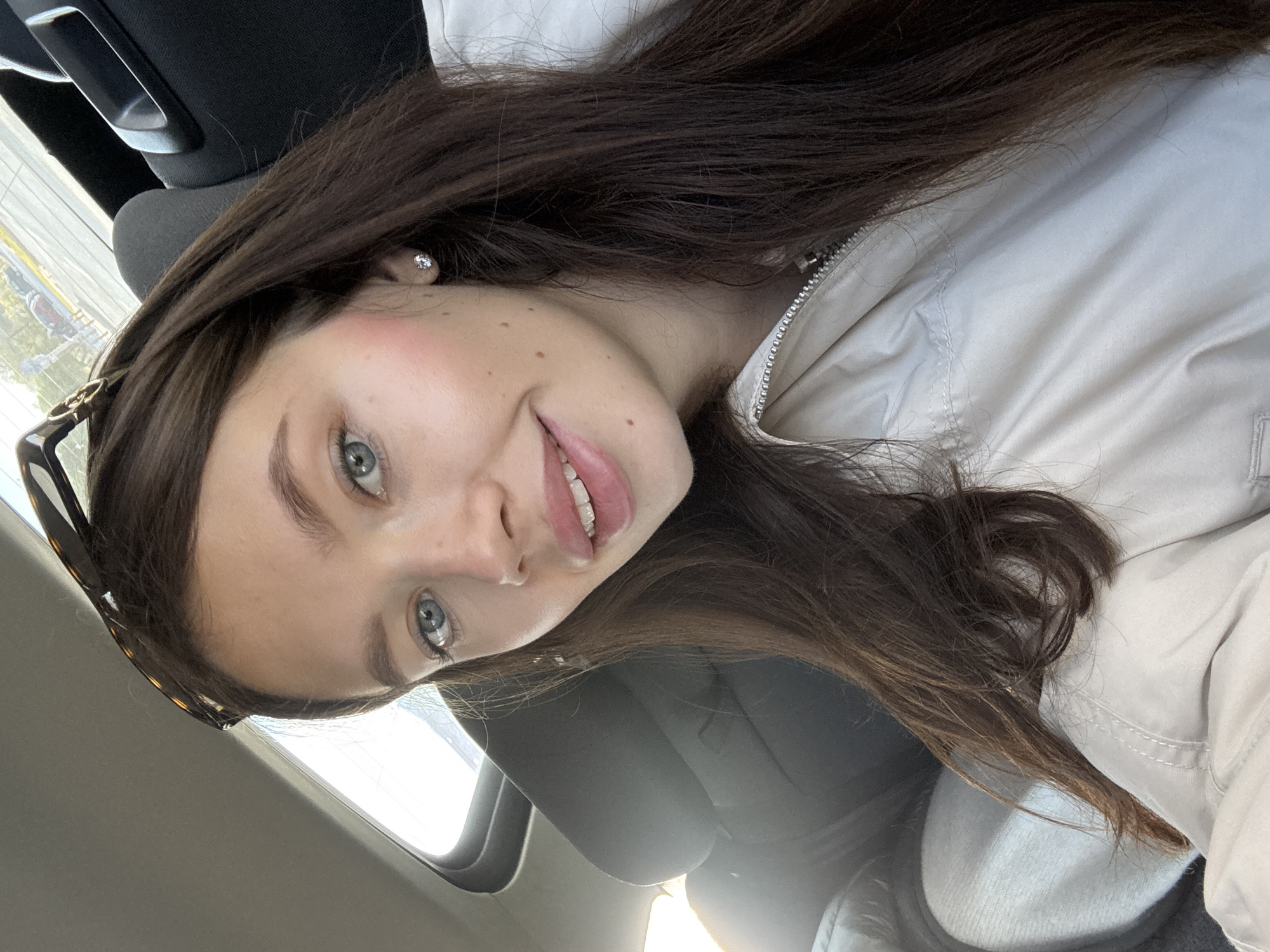 Woman takes smiling selfie in car passenger seat