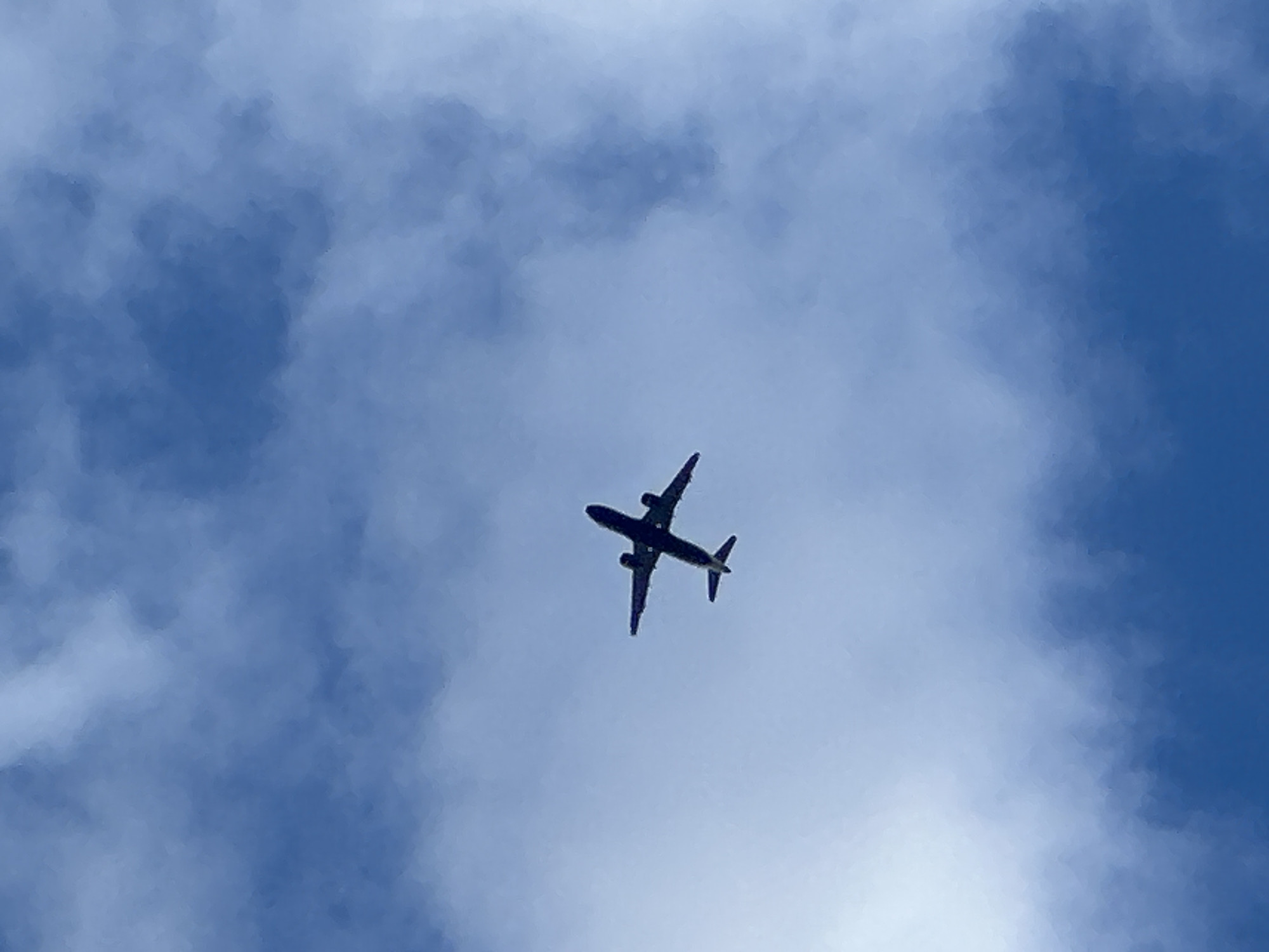 Aircraft passes overhead through patchy skies over southeast London
