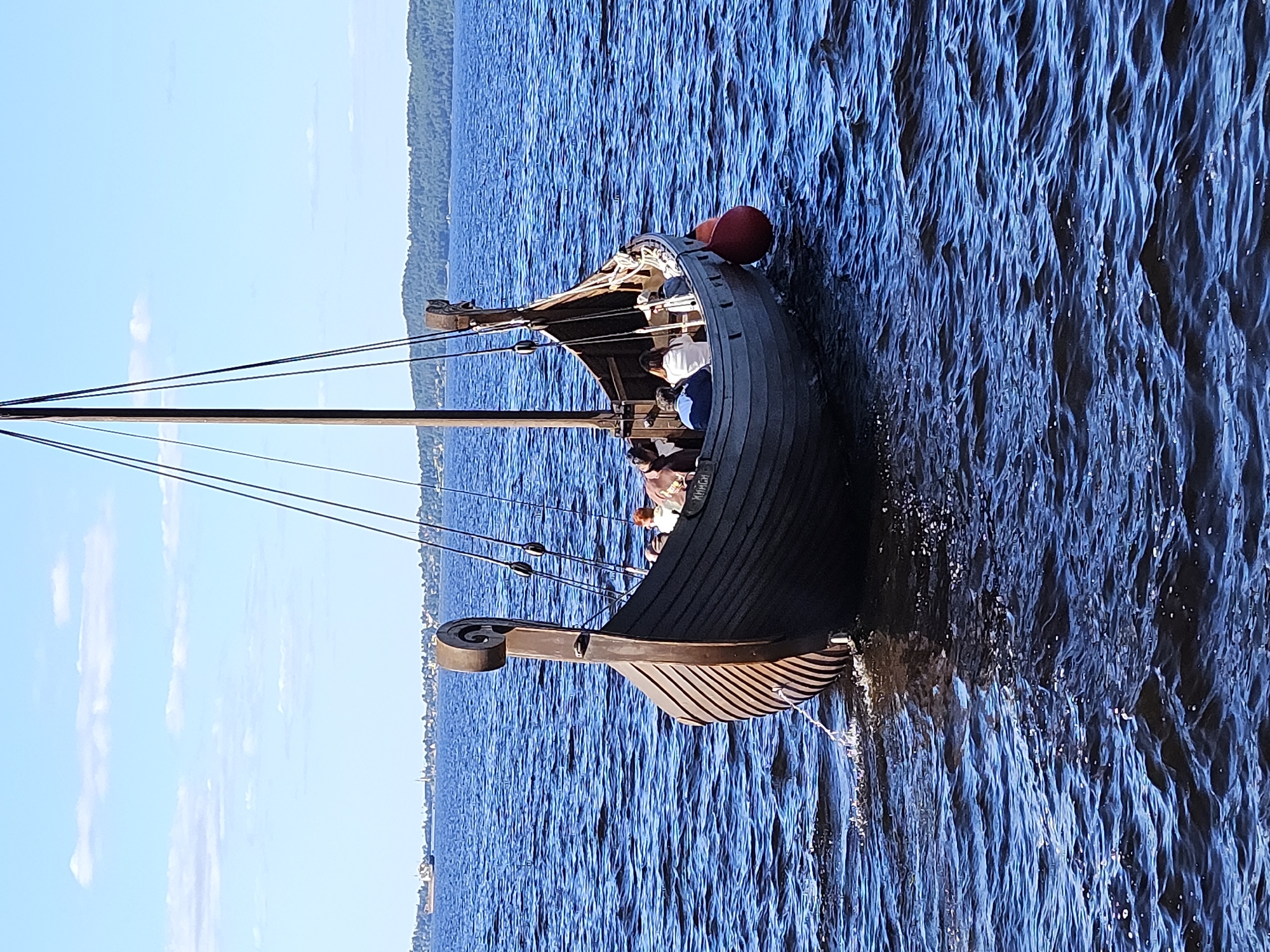 Viking ships, hydrofoils, and sculptures along a calm blue waterfront