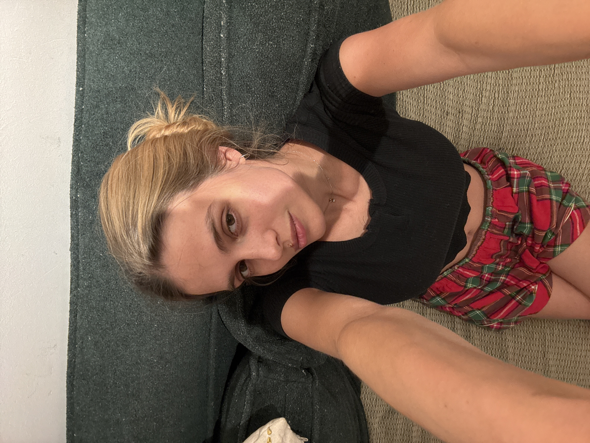 Woman takes selfie on couch in casual attire