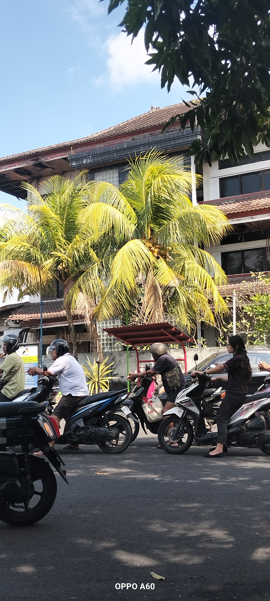 Street-level motorcycle traffic near a Denpasar gas station