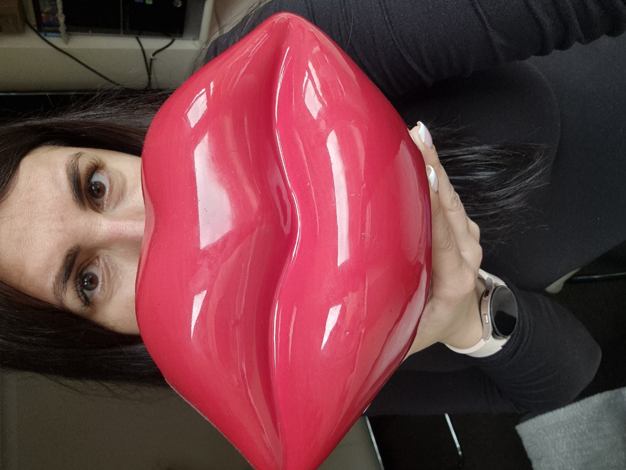 Woman poses playfully with giant red lips object in Suffolk