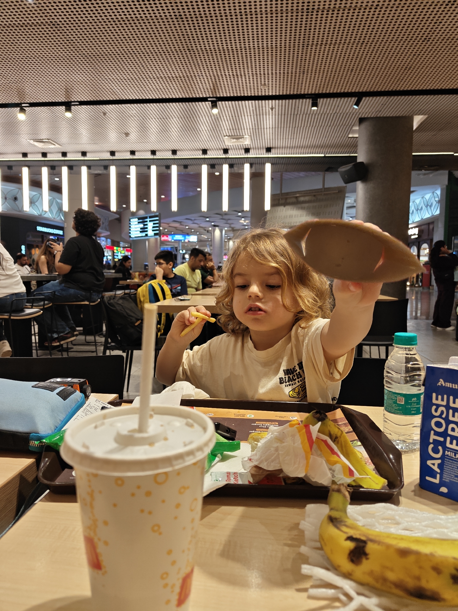 Child holds cardboard lid at Mumbai food court