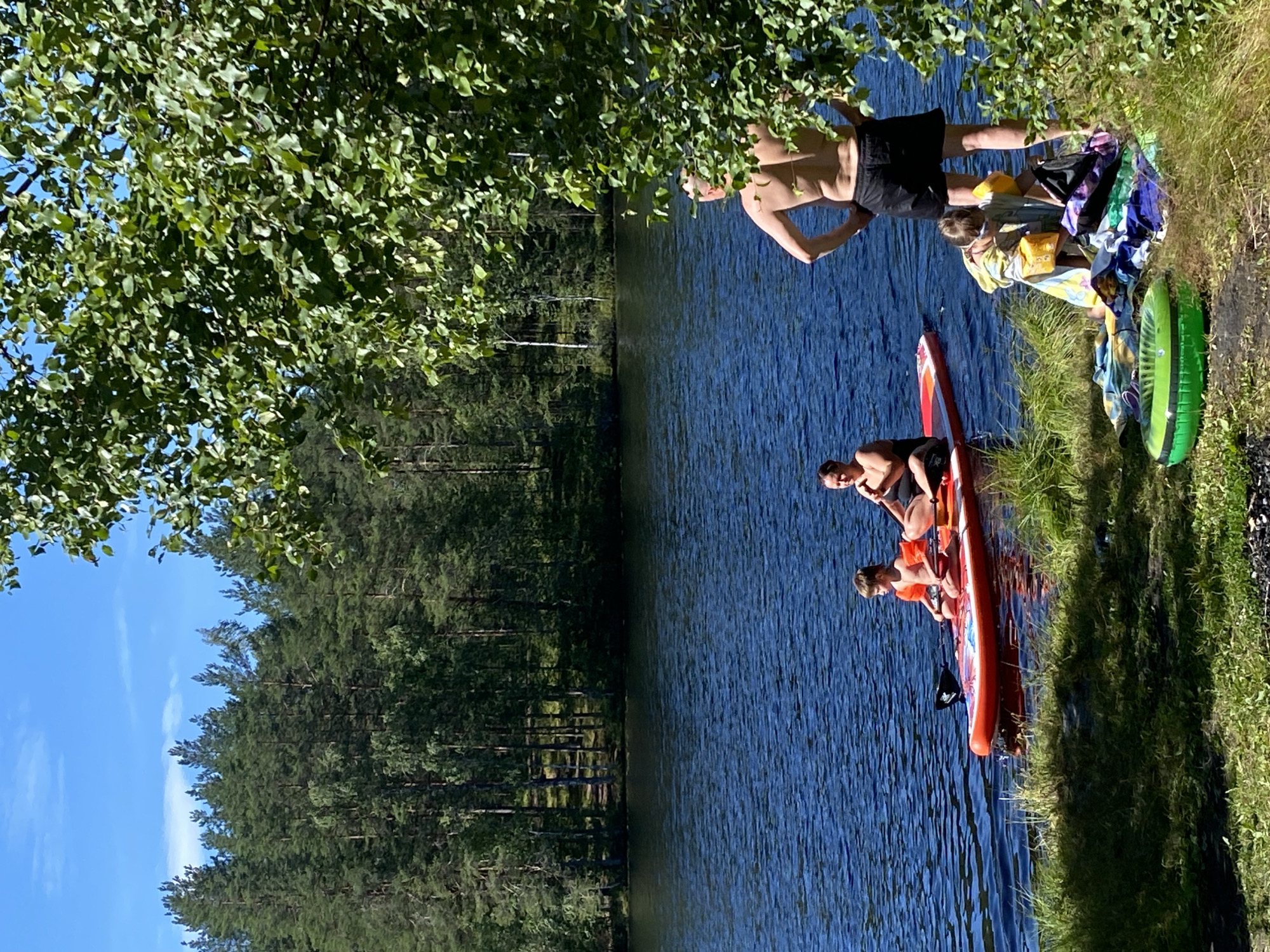 Summer lake day in Leipyasuo with rafts, paddleboards, and pine forest