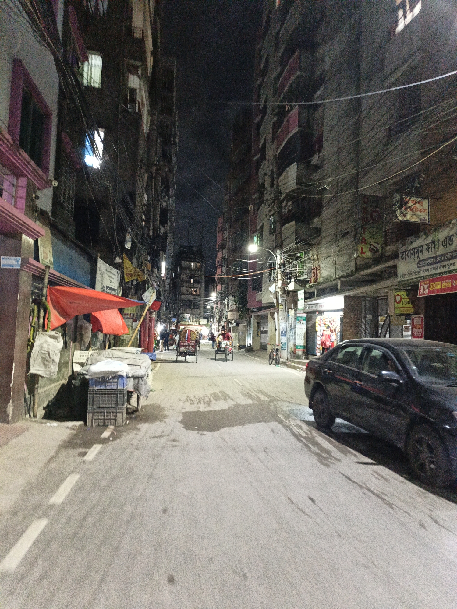 Nighttime street life in a dense Dhaka neighborhood