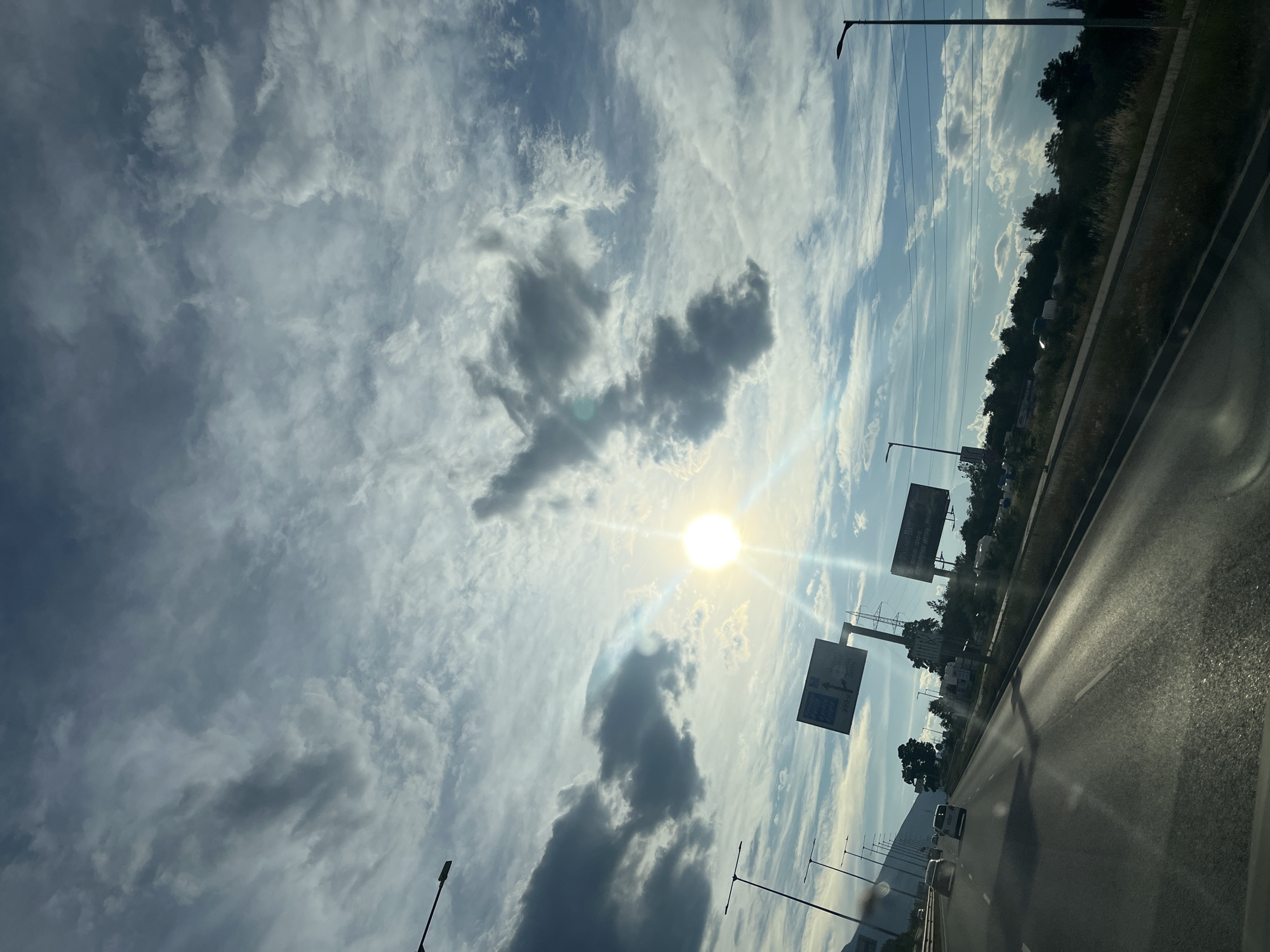 Highway drive under a dramatic, sun-breaking-through-clouds sky