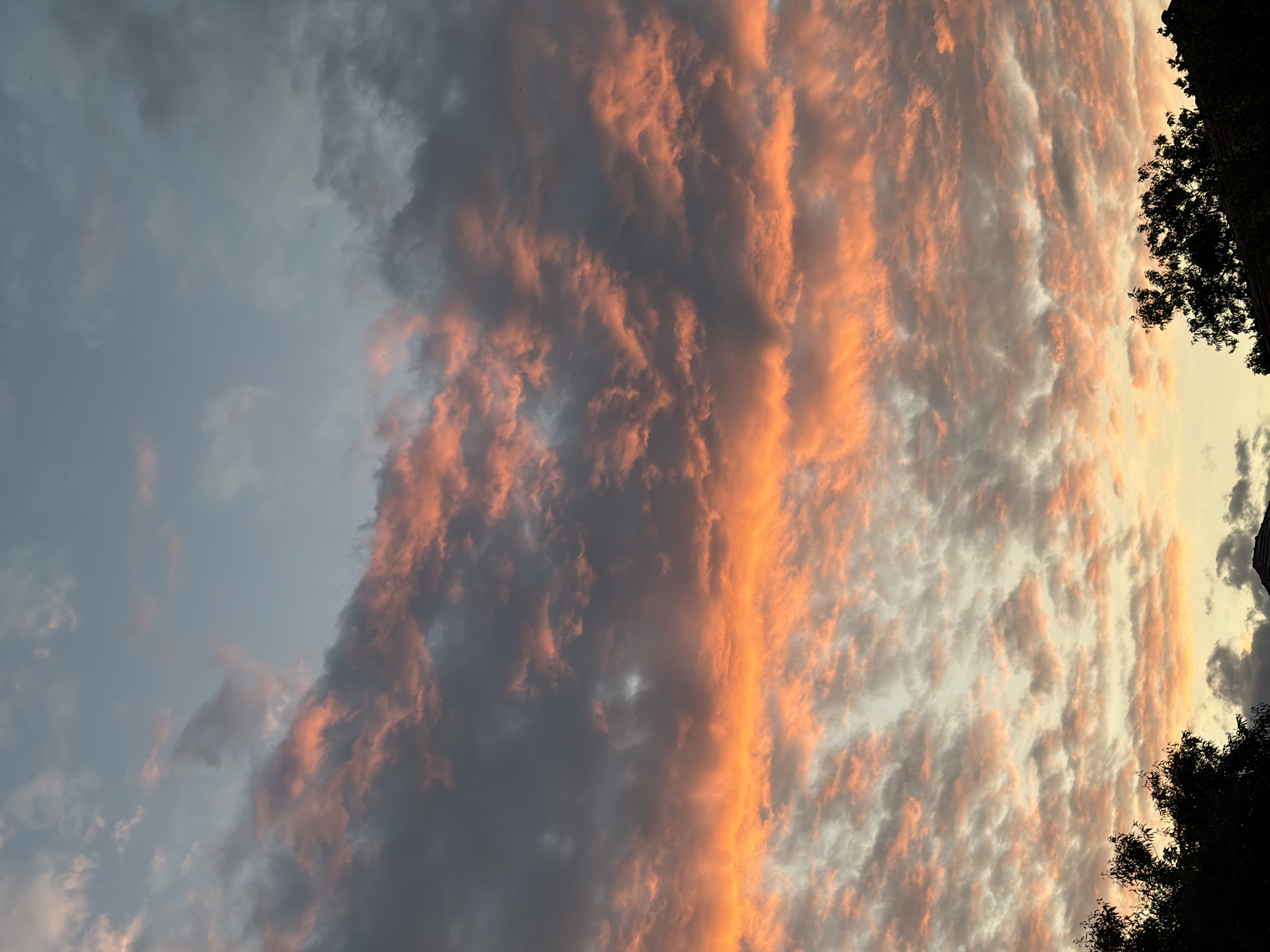 Sunset clouds display orange-pink hues over silhouetted landscape