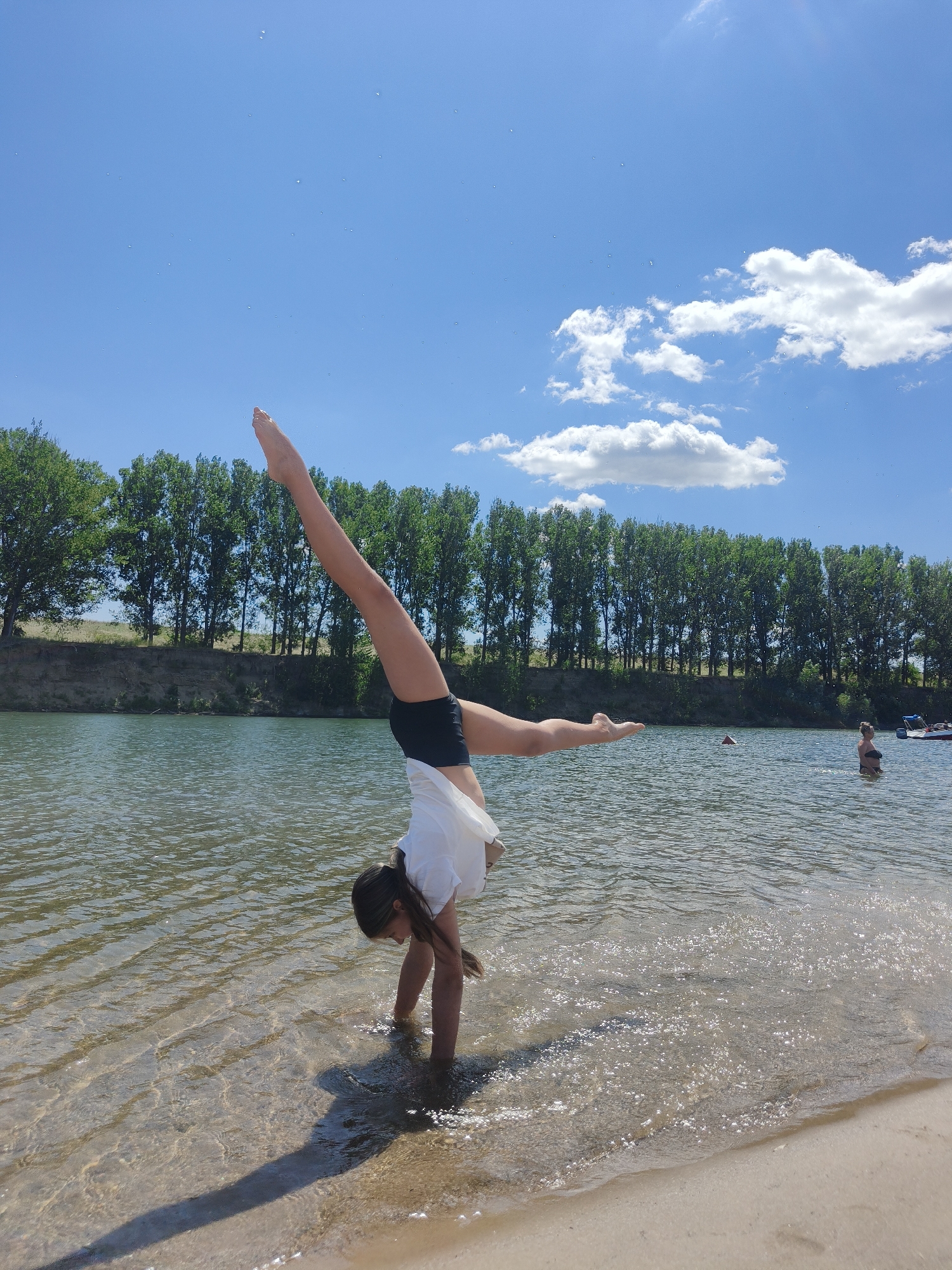 Handstand at the water's edge, legs up in the shallows