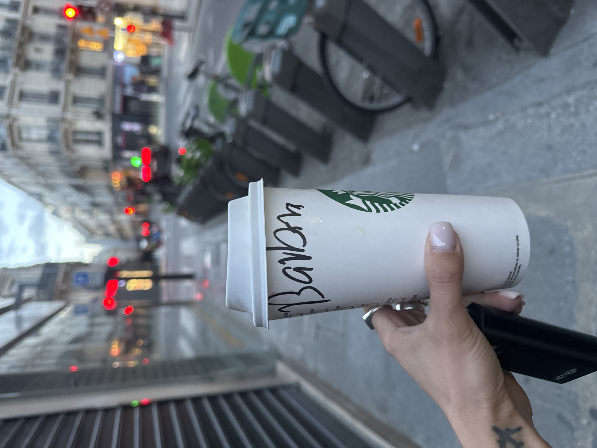 Person holds Starbucks cup and device on Paris street