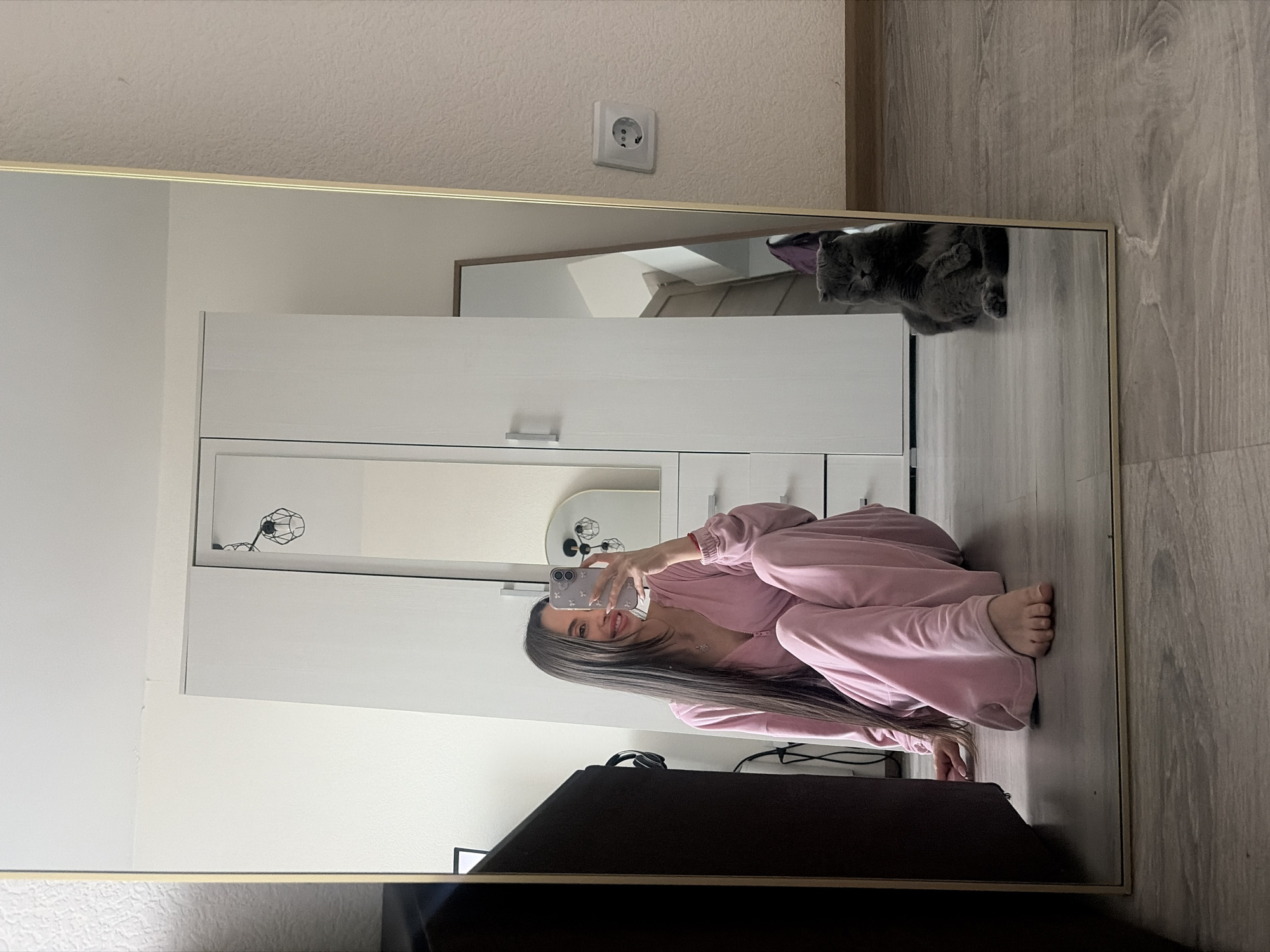 Woman takes playful selfies in pink tracksuit, Saint Petersburg apartment