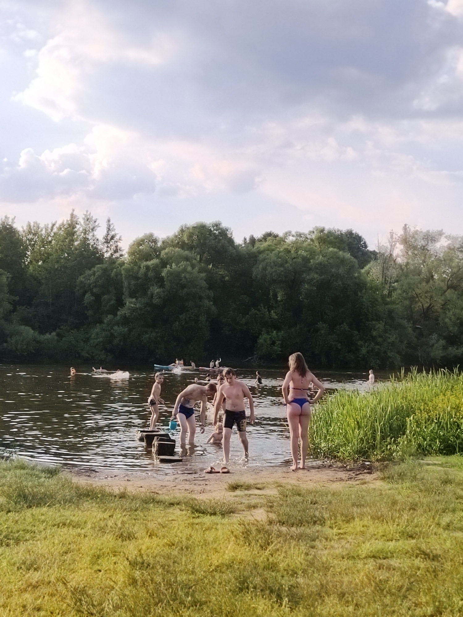 Summer waterfront gathering features swimming, paddleboarding and family recreation