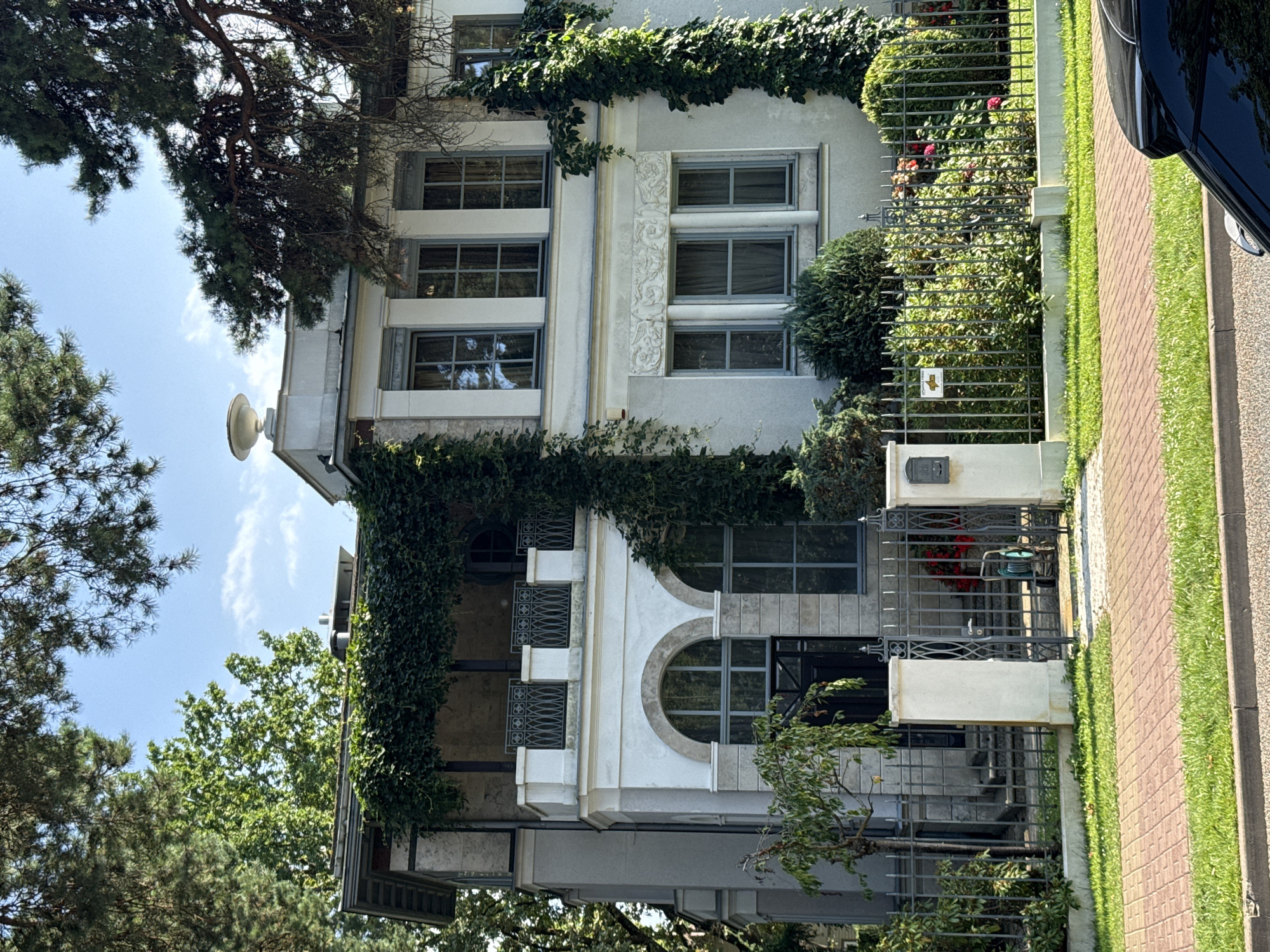 Ivy-covered white house behind iron gate in Jūrmala