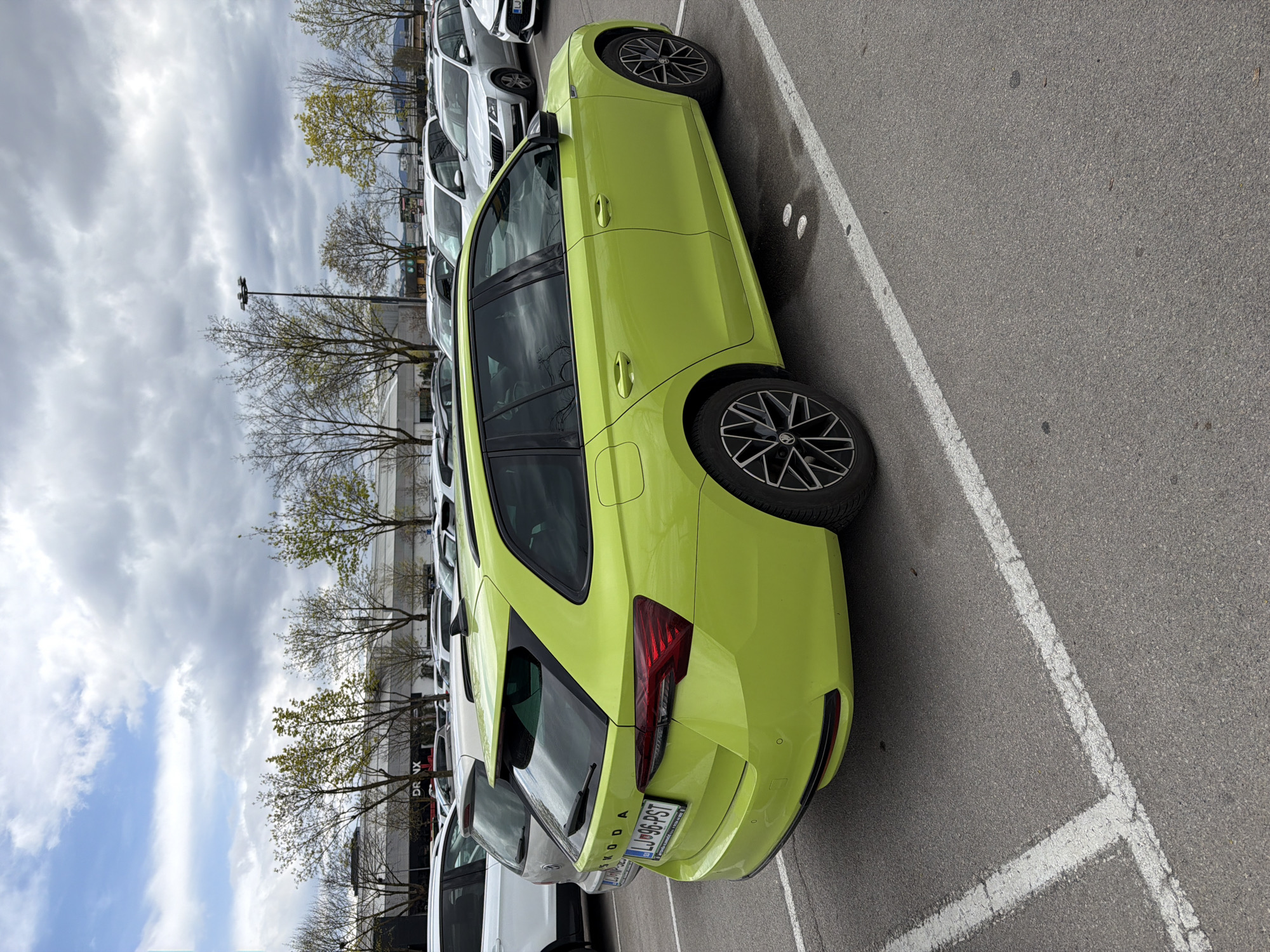 Green Skoda parked in Ljubljana lot under cloudy skies