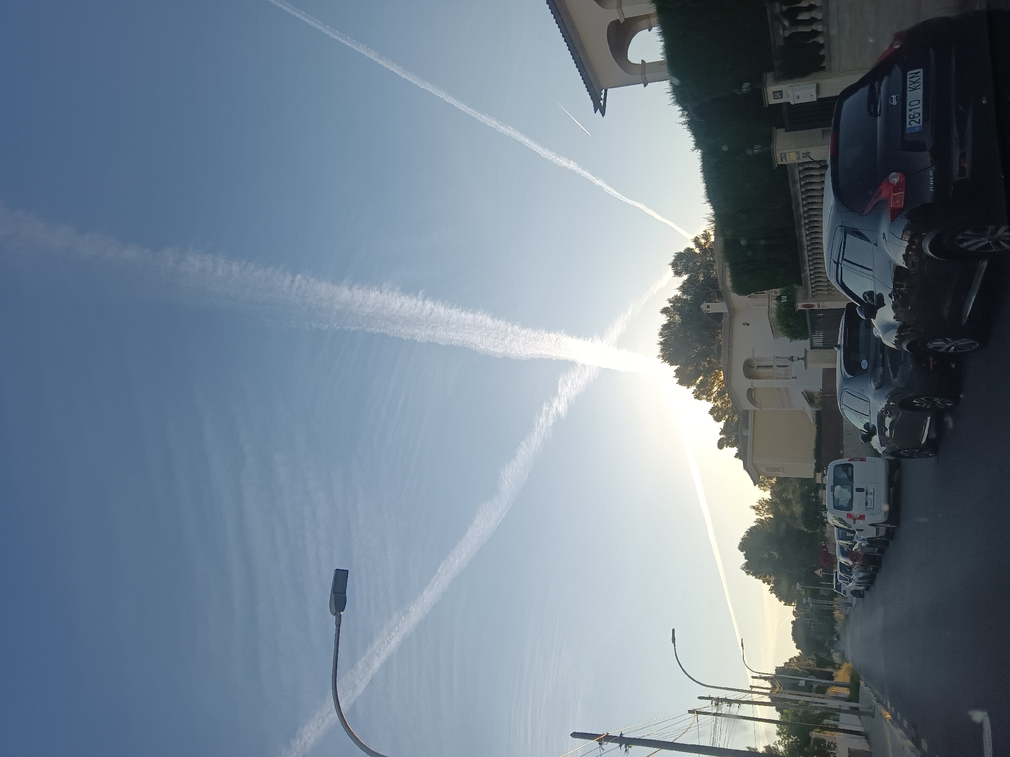 Street scene observed with contrails crossing blue sky