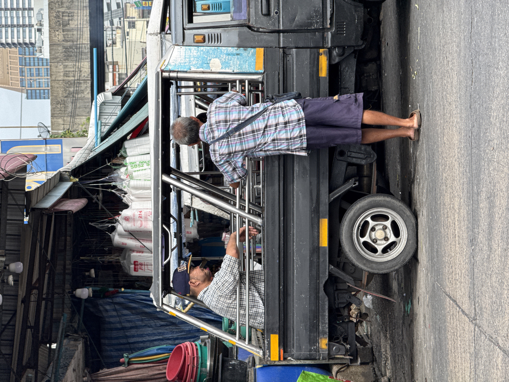 Two men ride songthaew taxi near Bangkok market