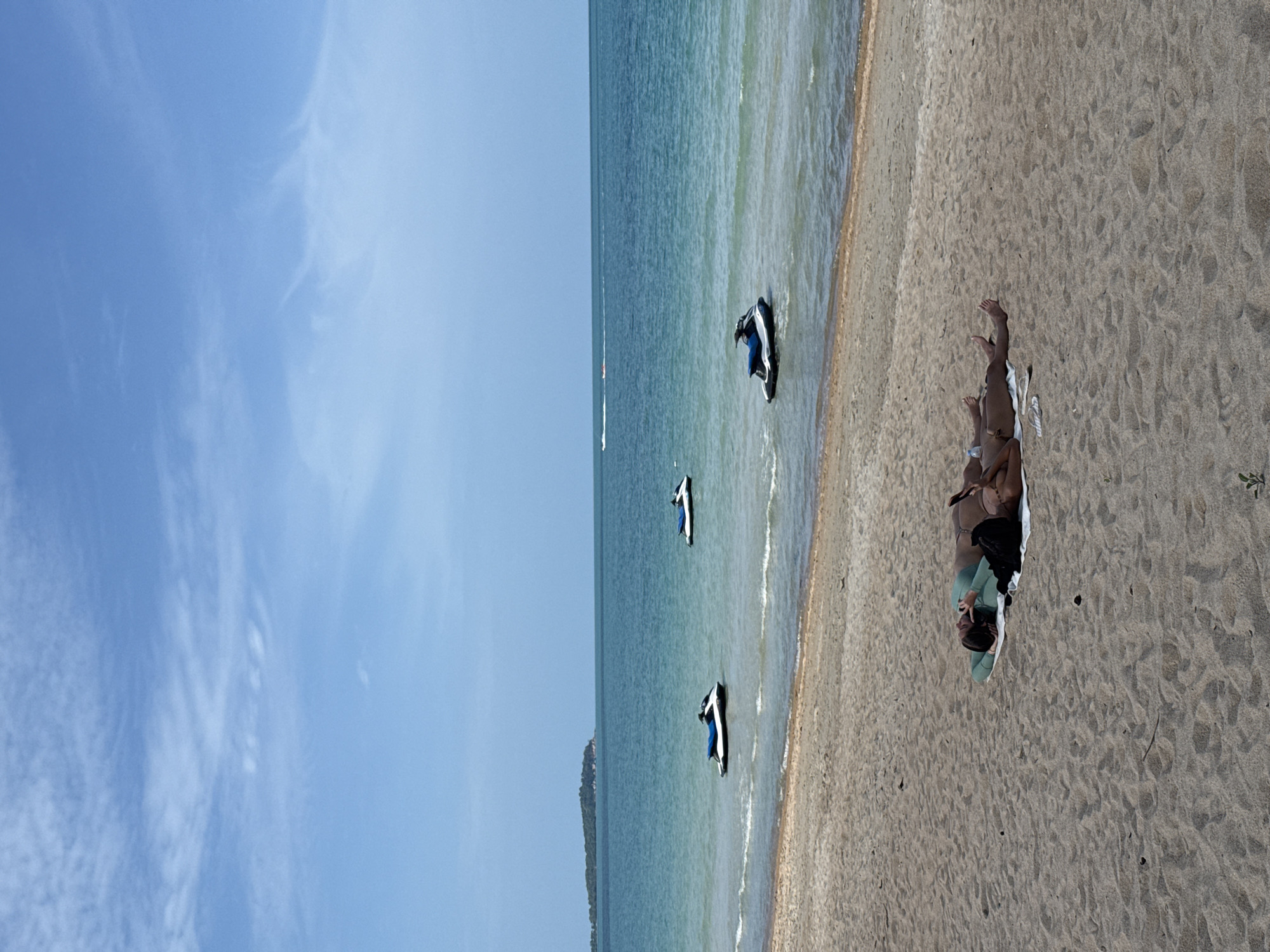 Busy beach morning on Ko Samui, jet skis and sunbathers in view.