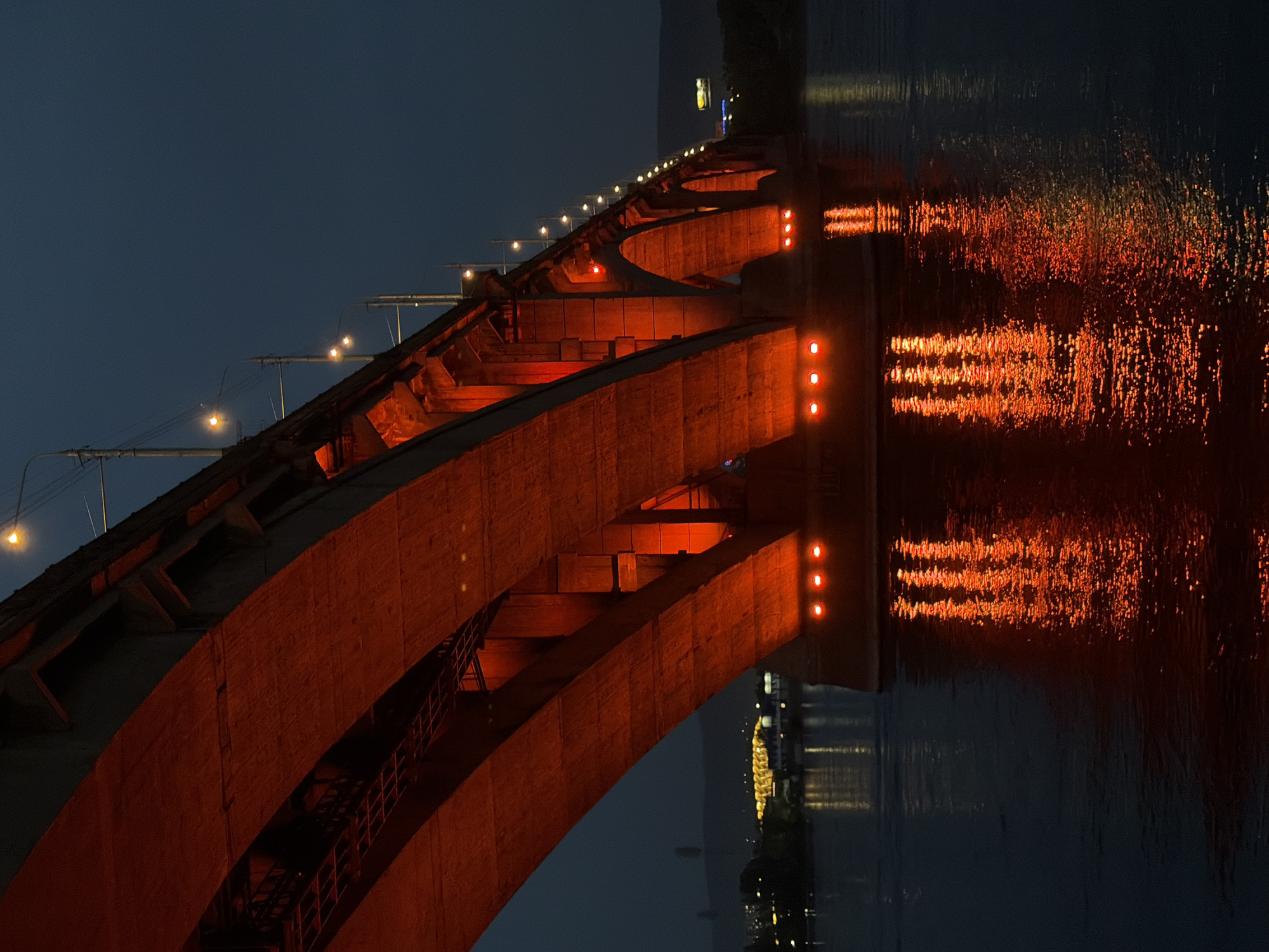 Red-lit bridges illuminate Yenisei River at dusk in Krasnoyarsk