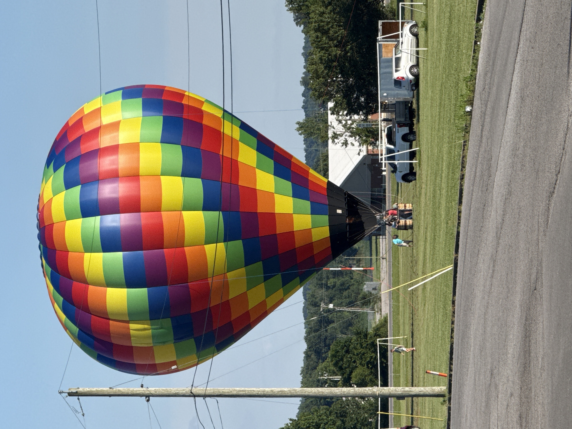 Rainbow hot air balloon lifts off from a Powderly field