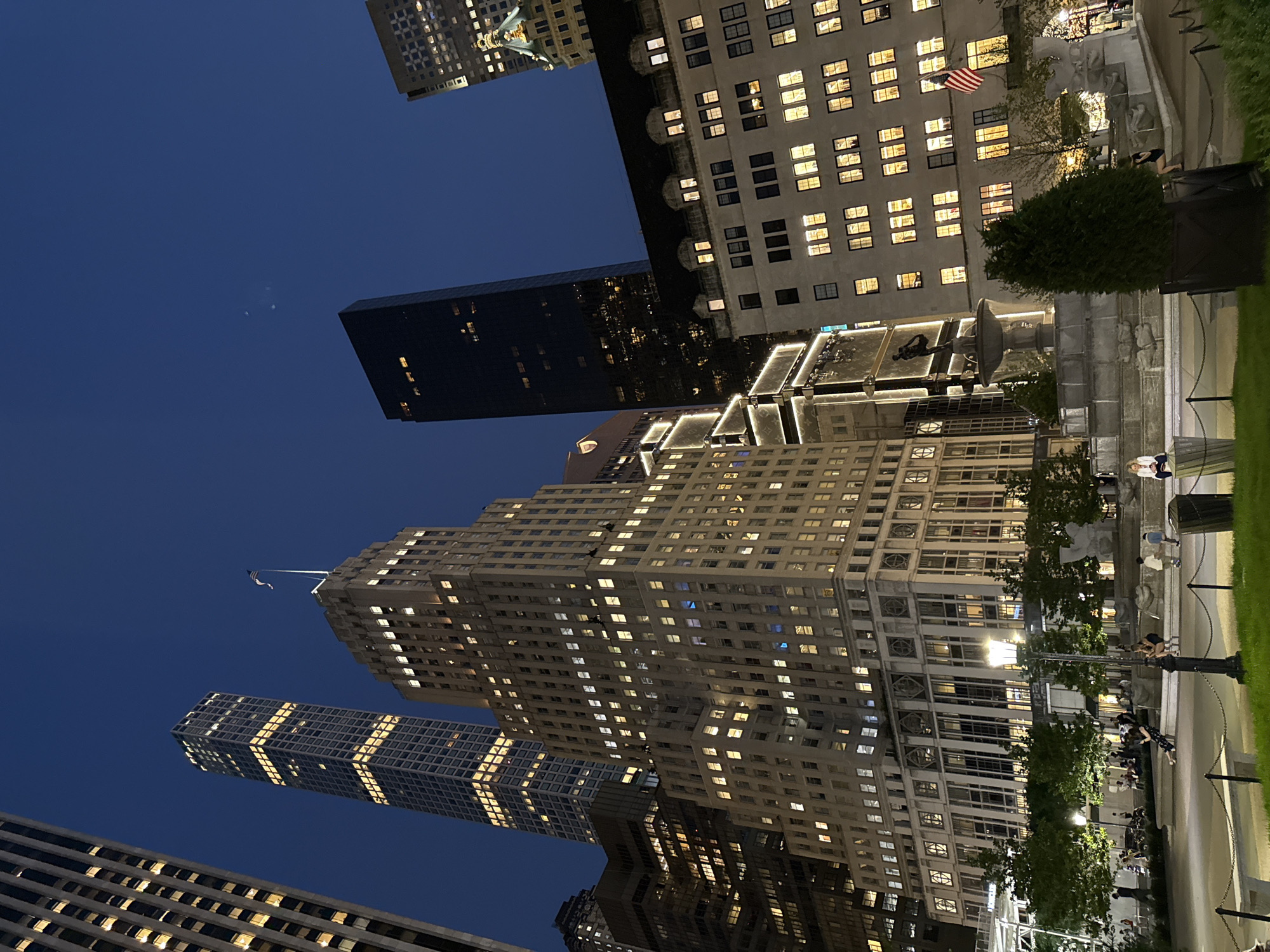 Midtown Manhattan glows at night from a public plaza