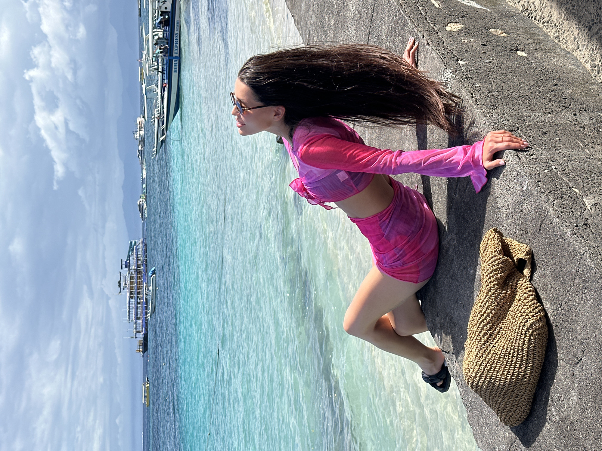 Woman visits Nusa Penida beach pier amid moored boats