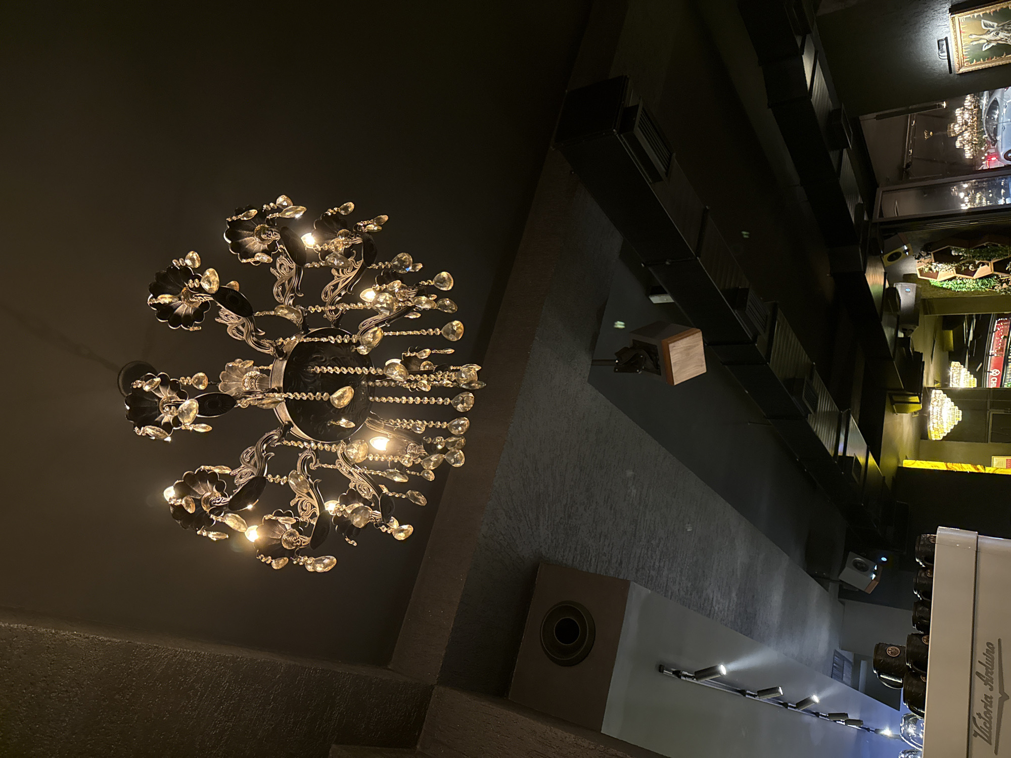 Coffee shop visitor films ornate chandelier during evening visit
