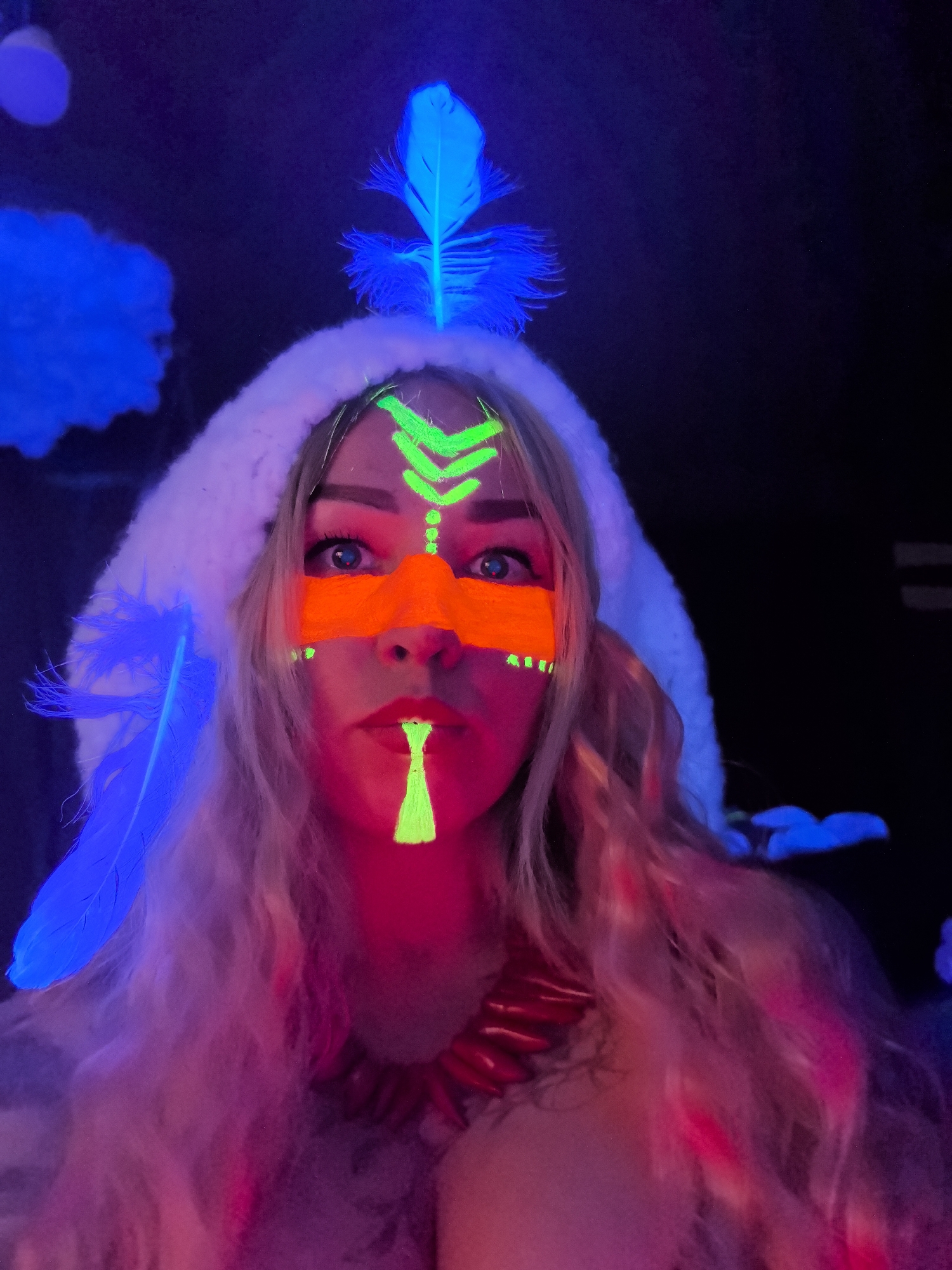 Woman photographed with glowing face paint under UV light