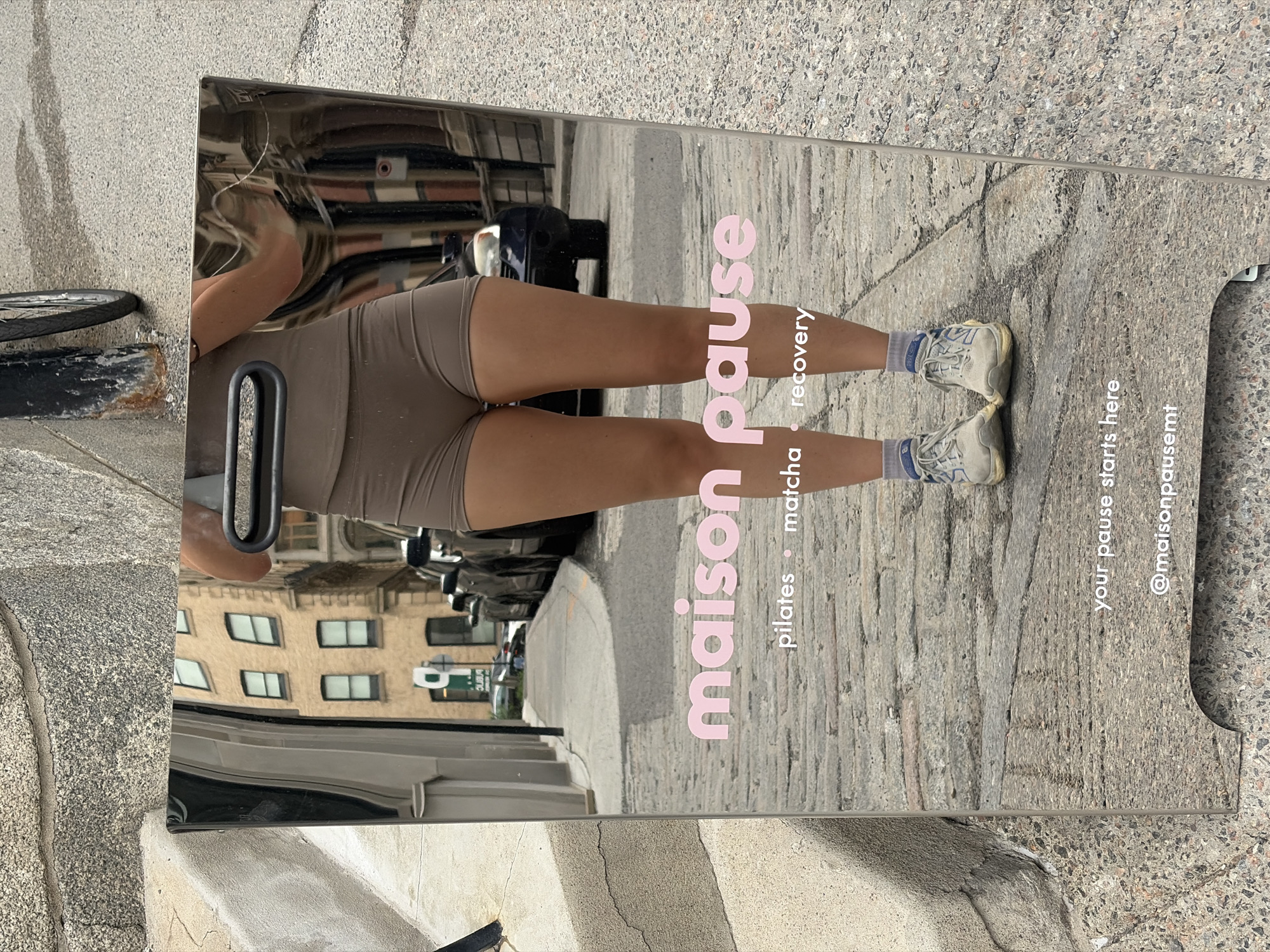 Woman's reflection captured in street mirror sign in Montreal