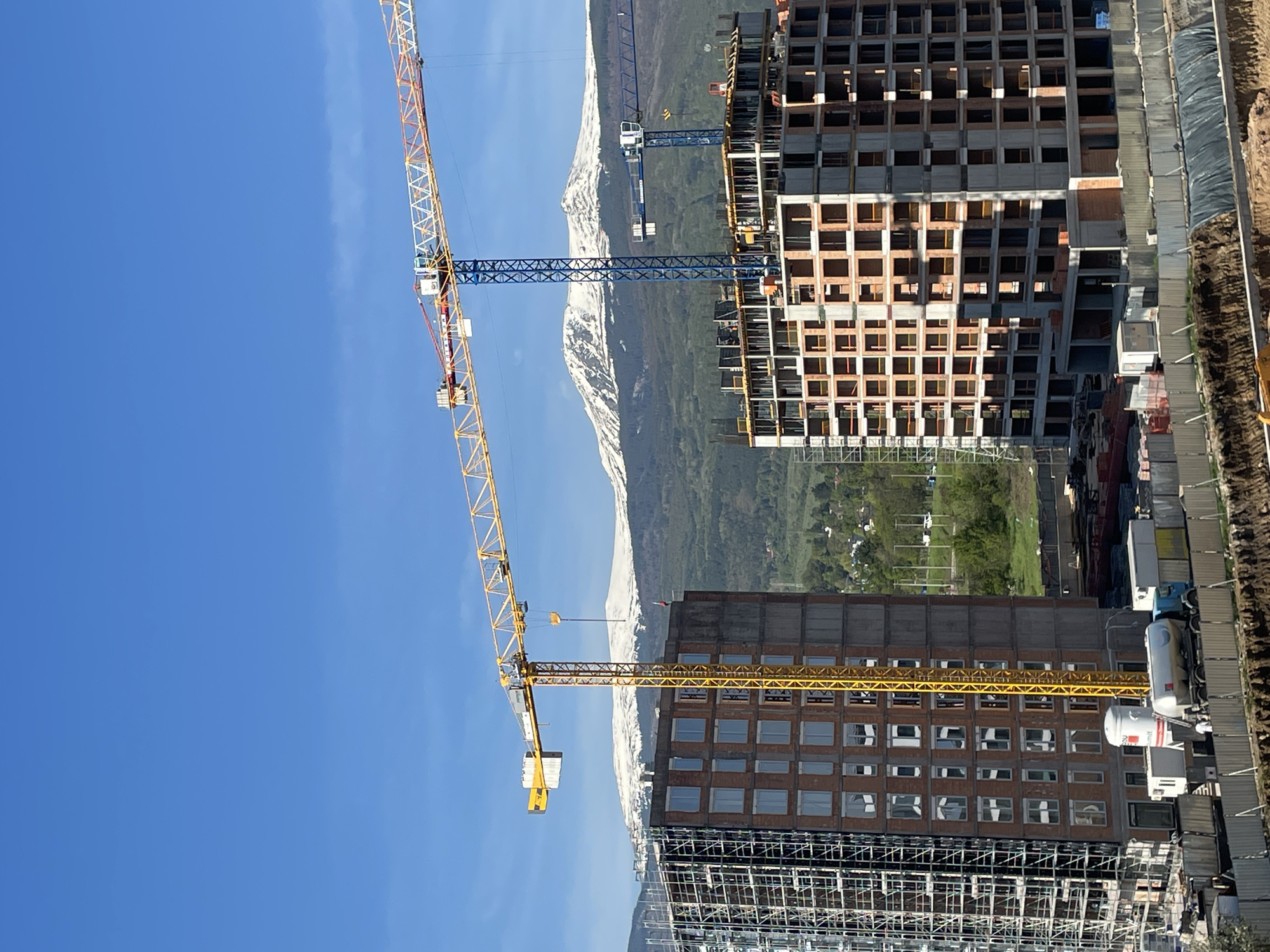 Construction cranes operate at Sofia building site against mountain backdrop