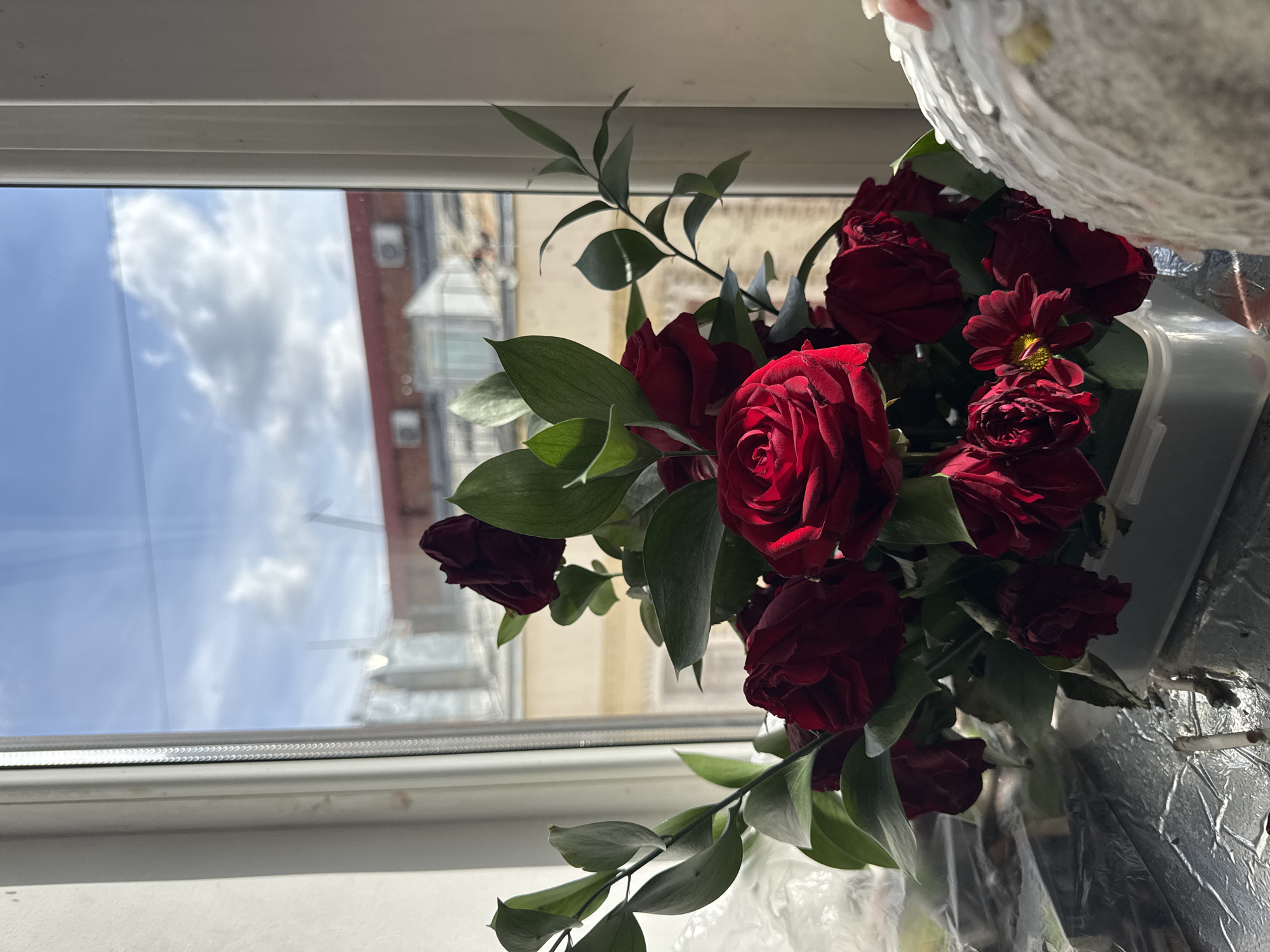 Red roses and chrysanthemums displayed by window in Moscow