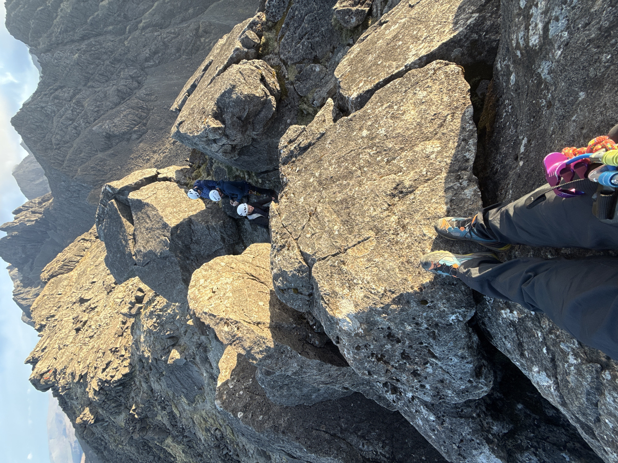 Three helmeted climbers spotted in rocky mountain terrain