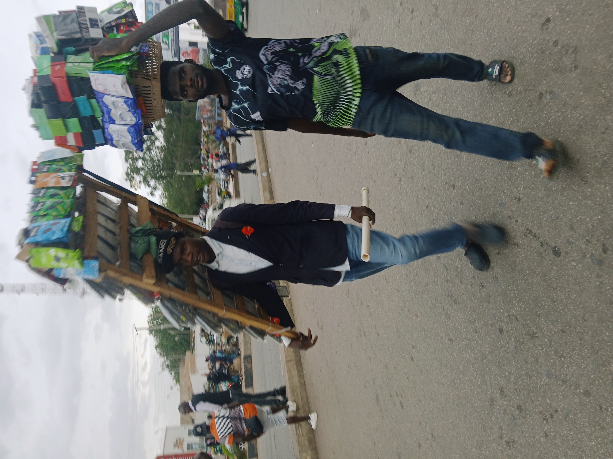 Men walking street in Jos, one carrying goods