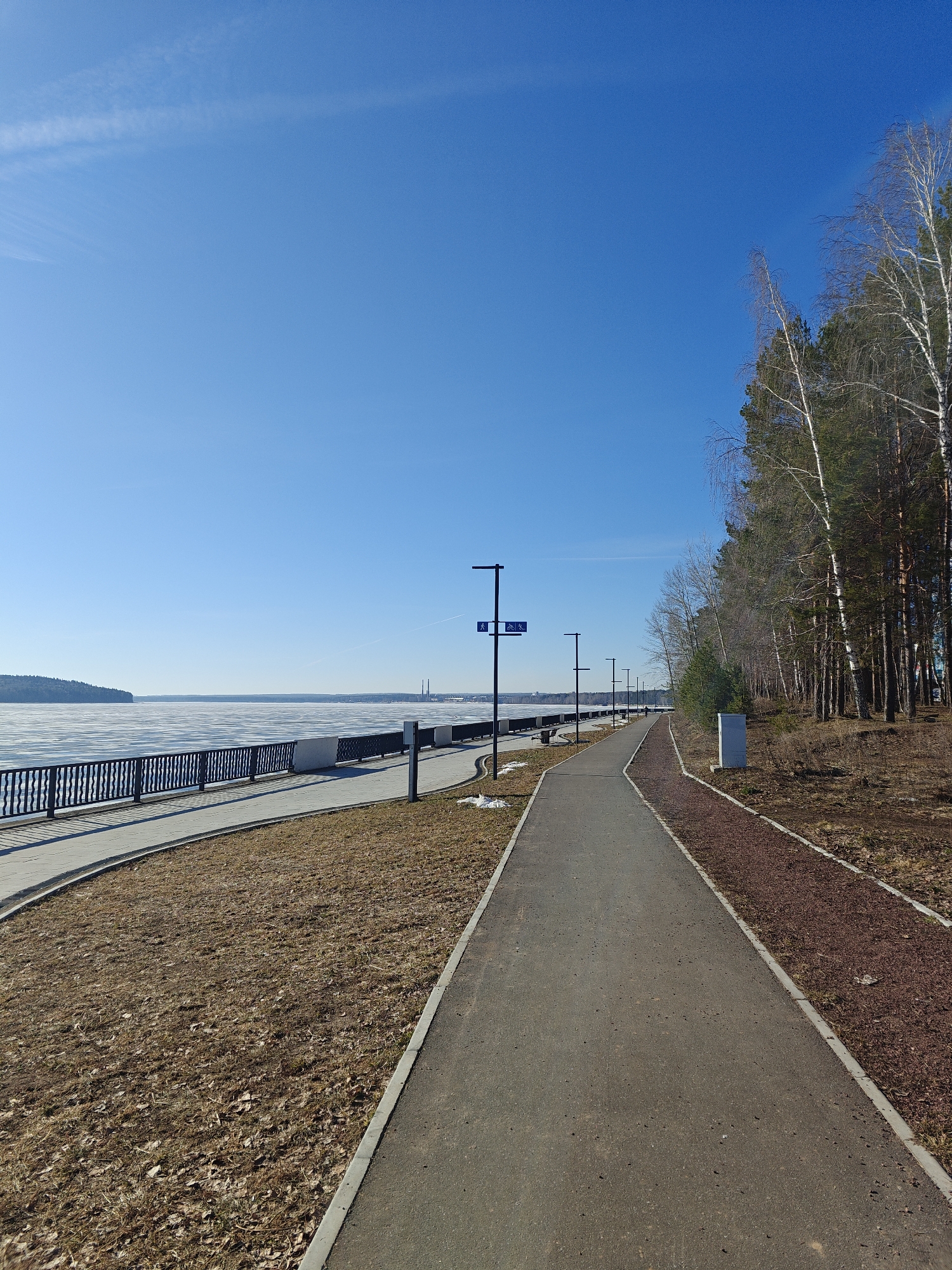 Early morning cyclist rides frozen reservoir path in Chaikovsky