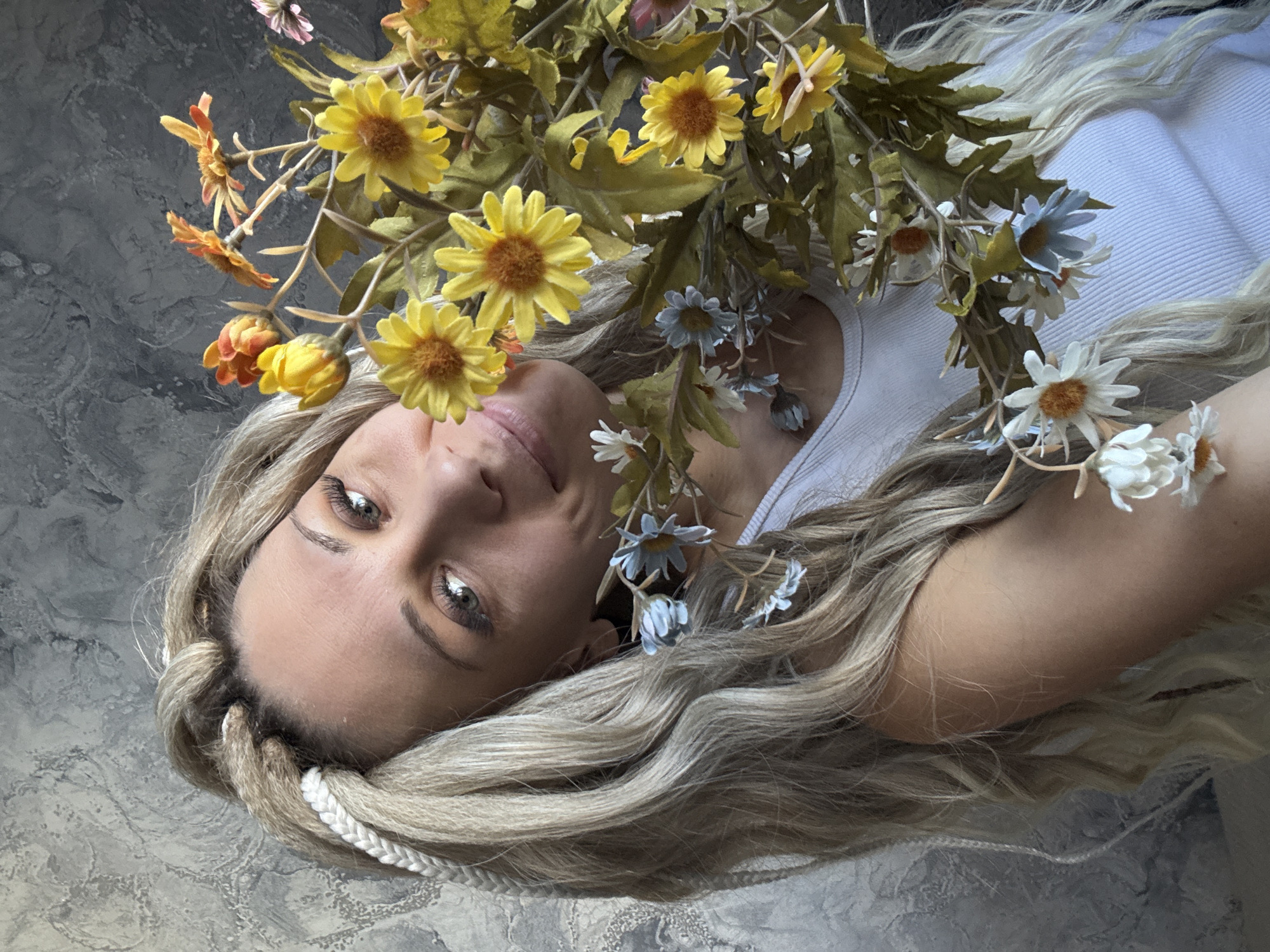 Woman poses with flower crown on gray surface in Russia