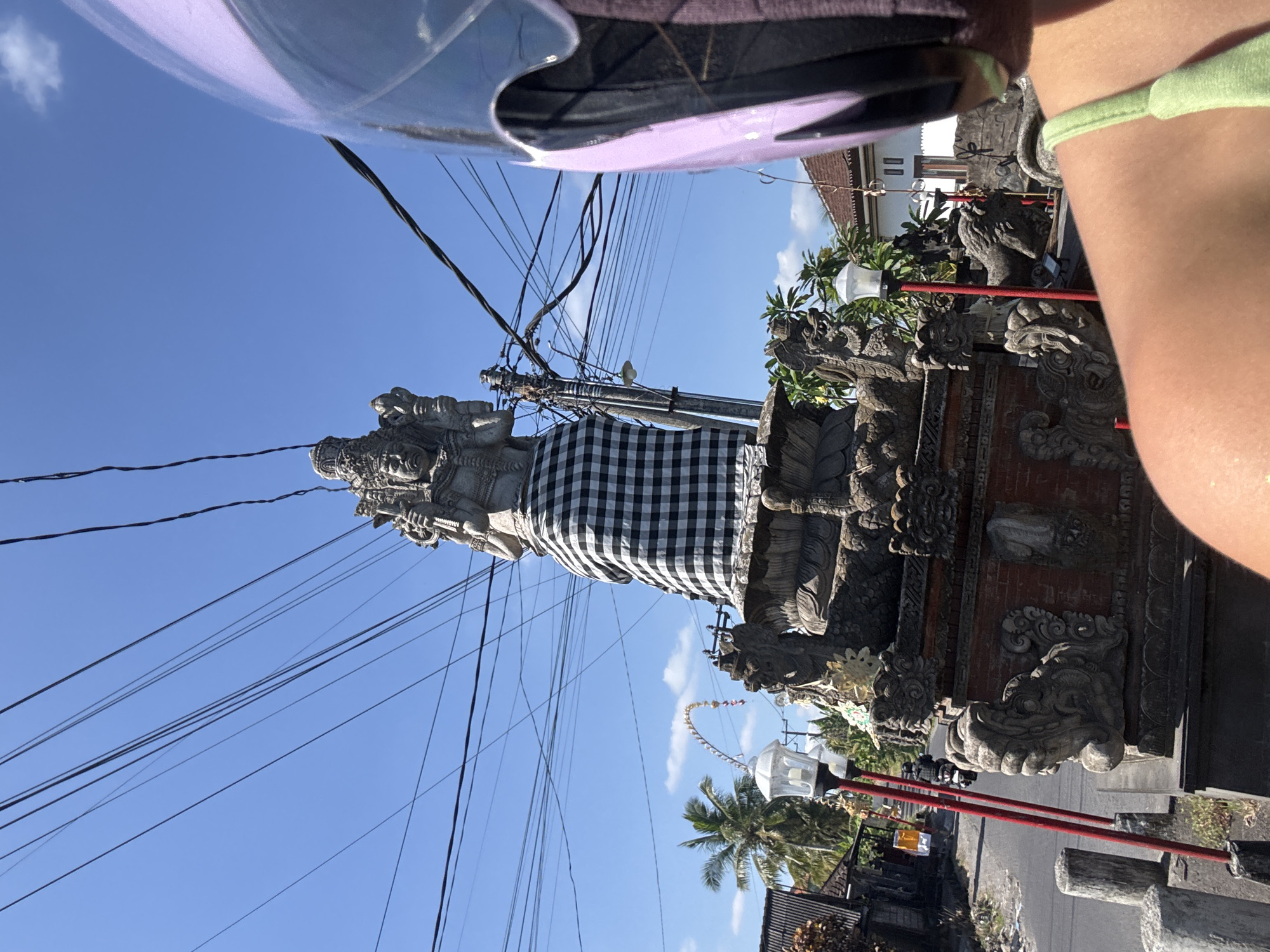 Scooter ride past a ceremonial statue in Kediri, Indonesia