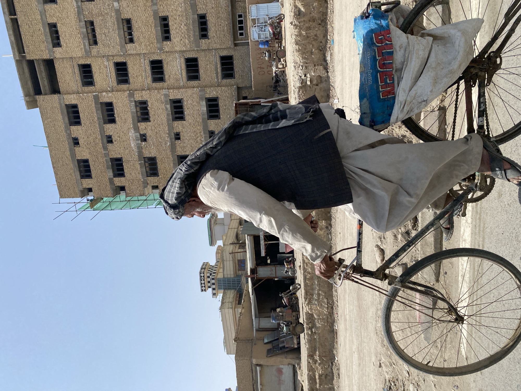 Everyday riders navigate Kandahar streets on bikes and motorcycle.